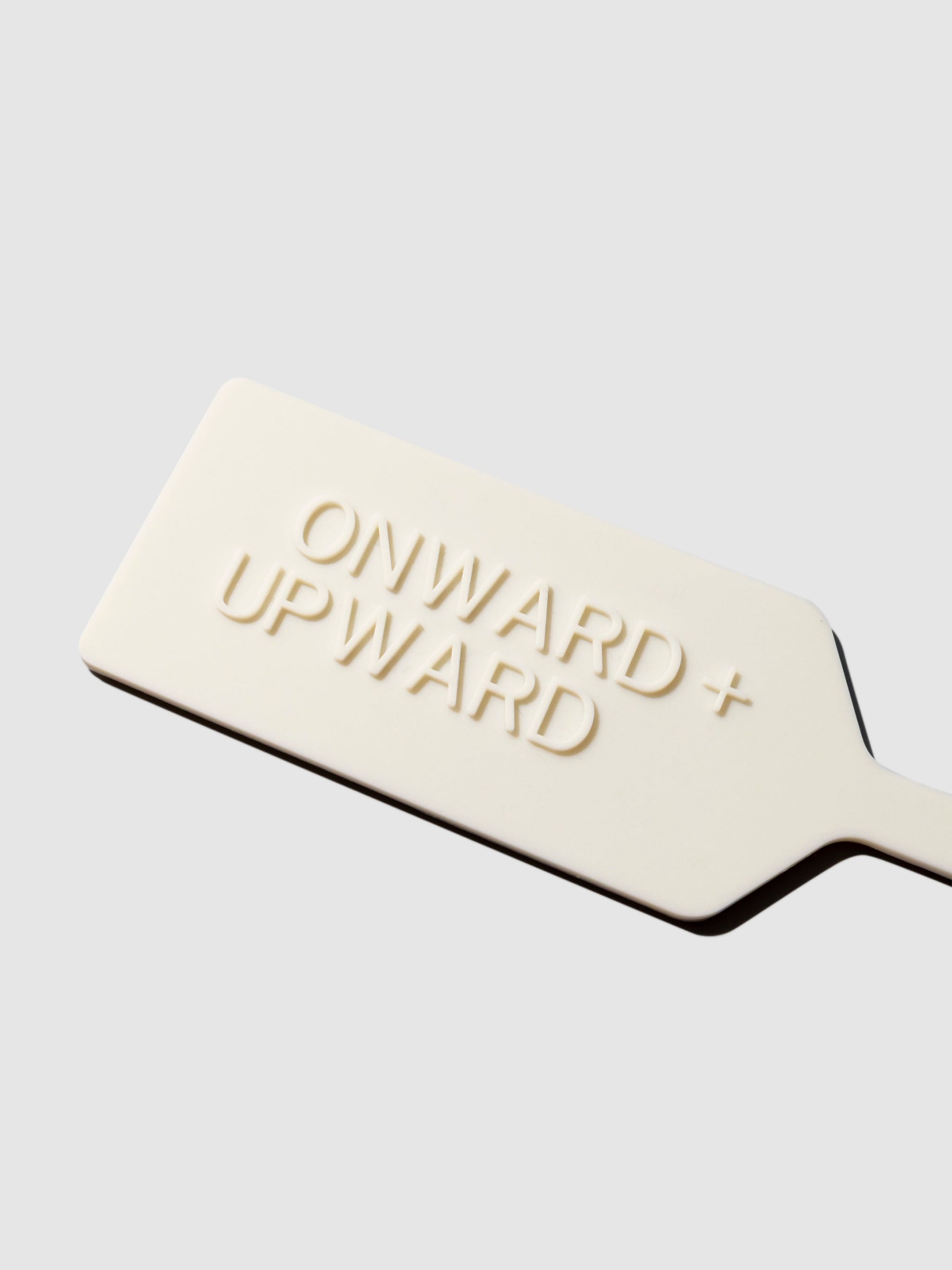 Closeup of luggage tag with text that reads "Onward + Upward"