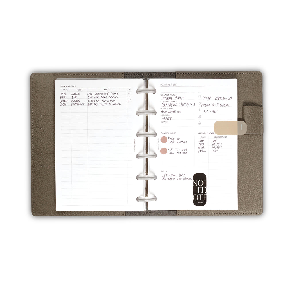 Insert in use inside a Fossil leather folio. The plant care log and inventory pages are filled out and decorated with page flags and color drop stickers.