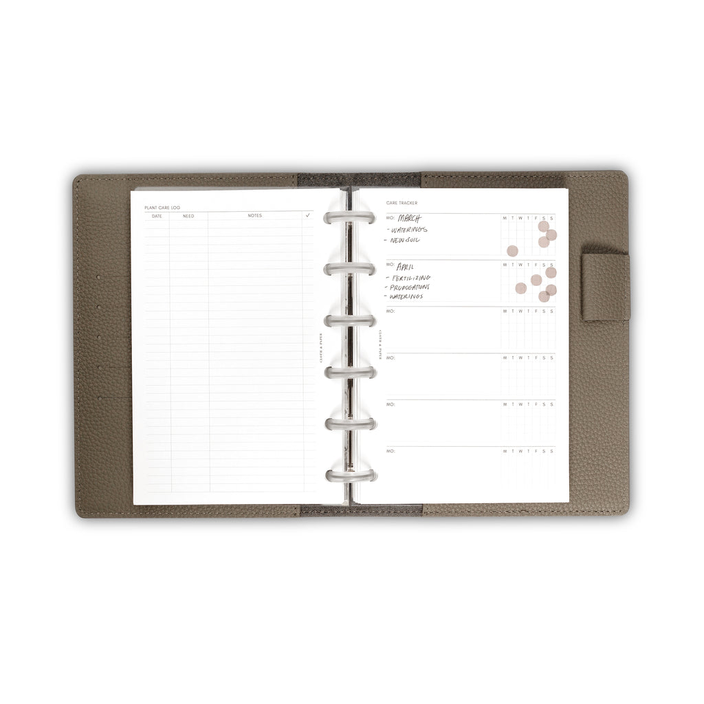 Inserts in use inside a Fossil leather folio. The care tracker sheet is filled out in ink, and the weekly tracker is filled in with brown dot stickers marking the days of the week a task was completed.