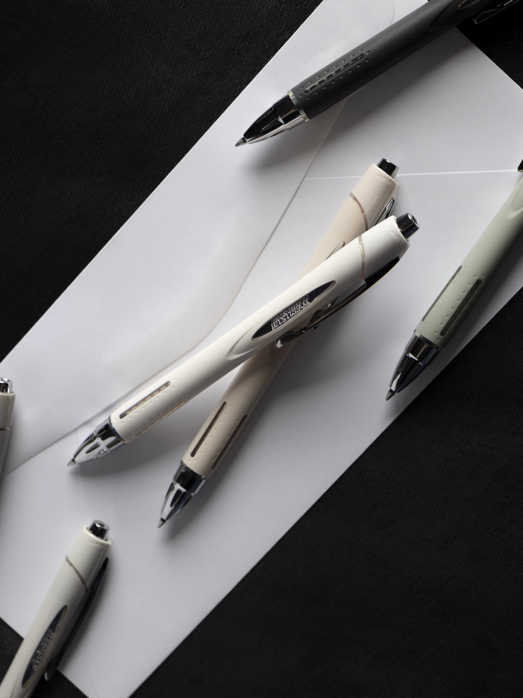 Uni Jetstream RT Ballpoint Pens on an envelope against a black background.