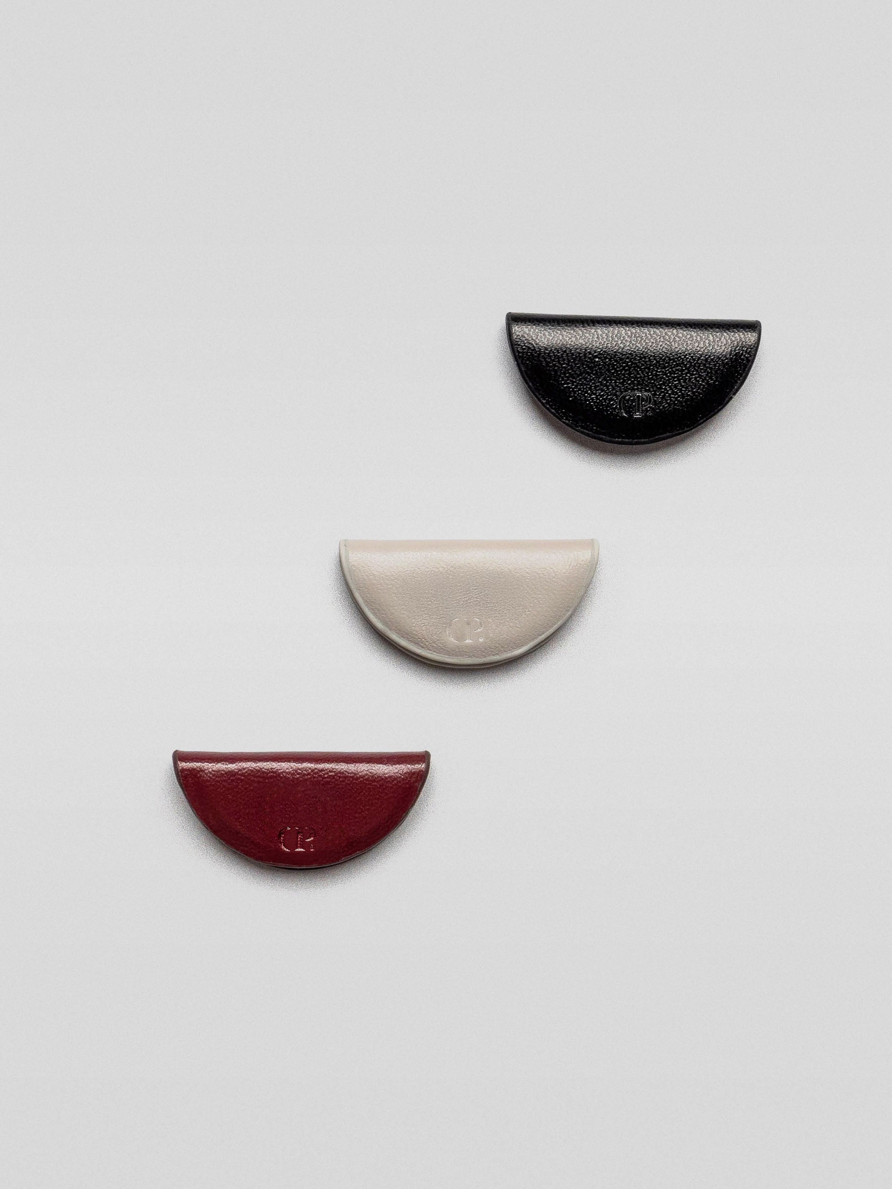 Three magnetic leather bookmarks from the Mini eCLIPse Set | Vol. 2 laid out individually on a flat surface, showing black, cream, and burgundy colors.