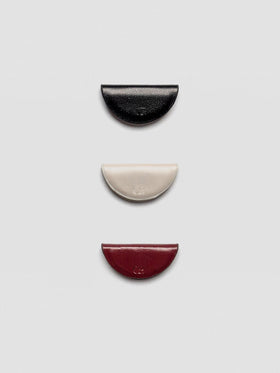 A set of three semi-circle leather magnetic bookmarks in black, cream, and burgundy colors