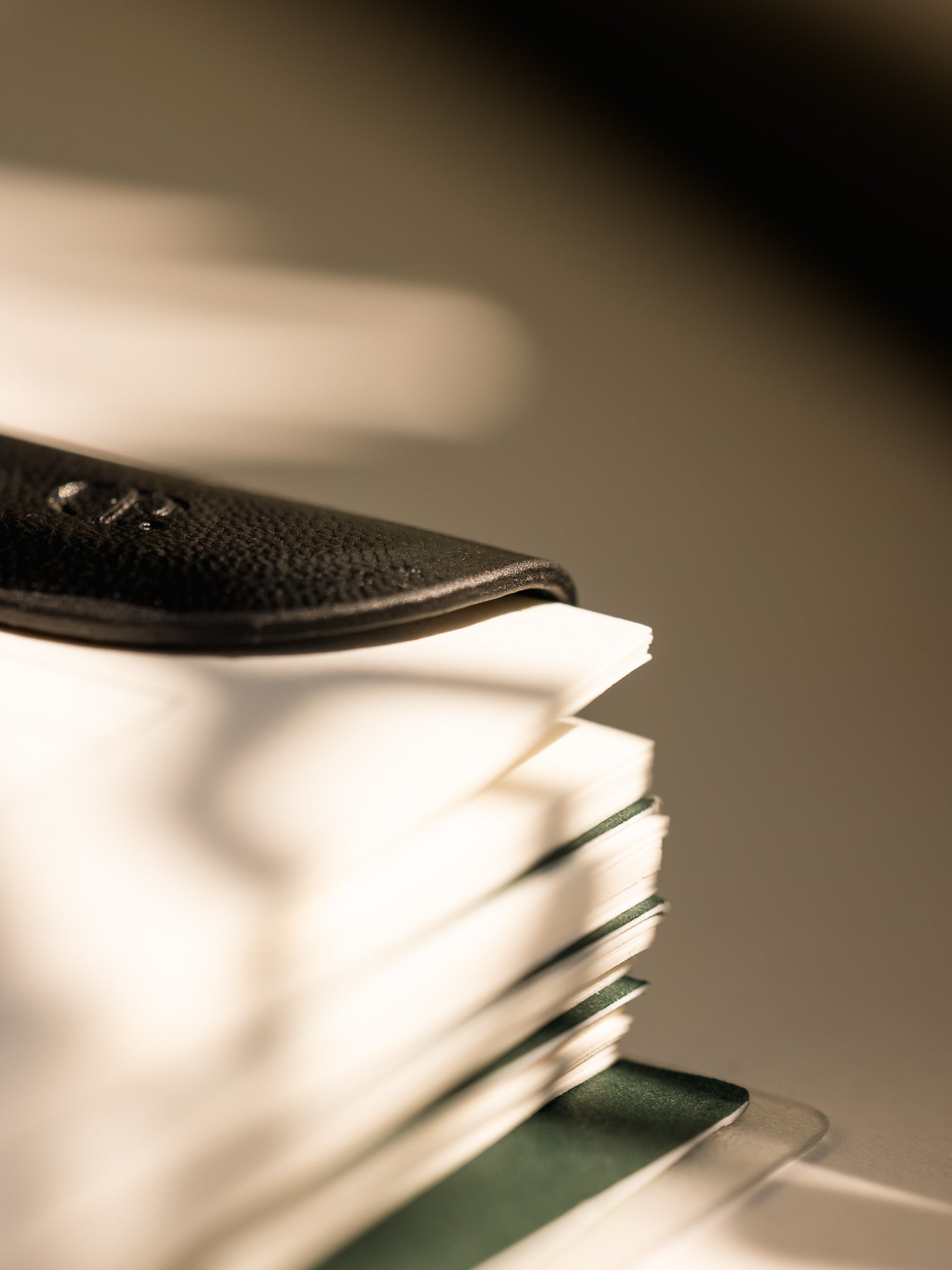 A black Mini eCLIPse bookmark clipped onto the pages of a stacked planner, highlighting its sleek design and low profile.