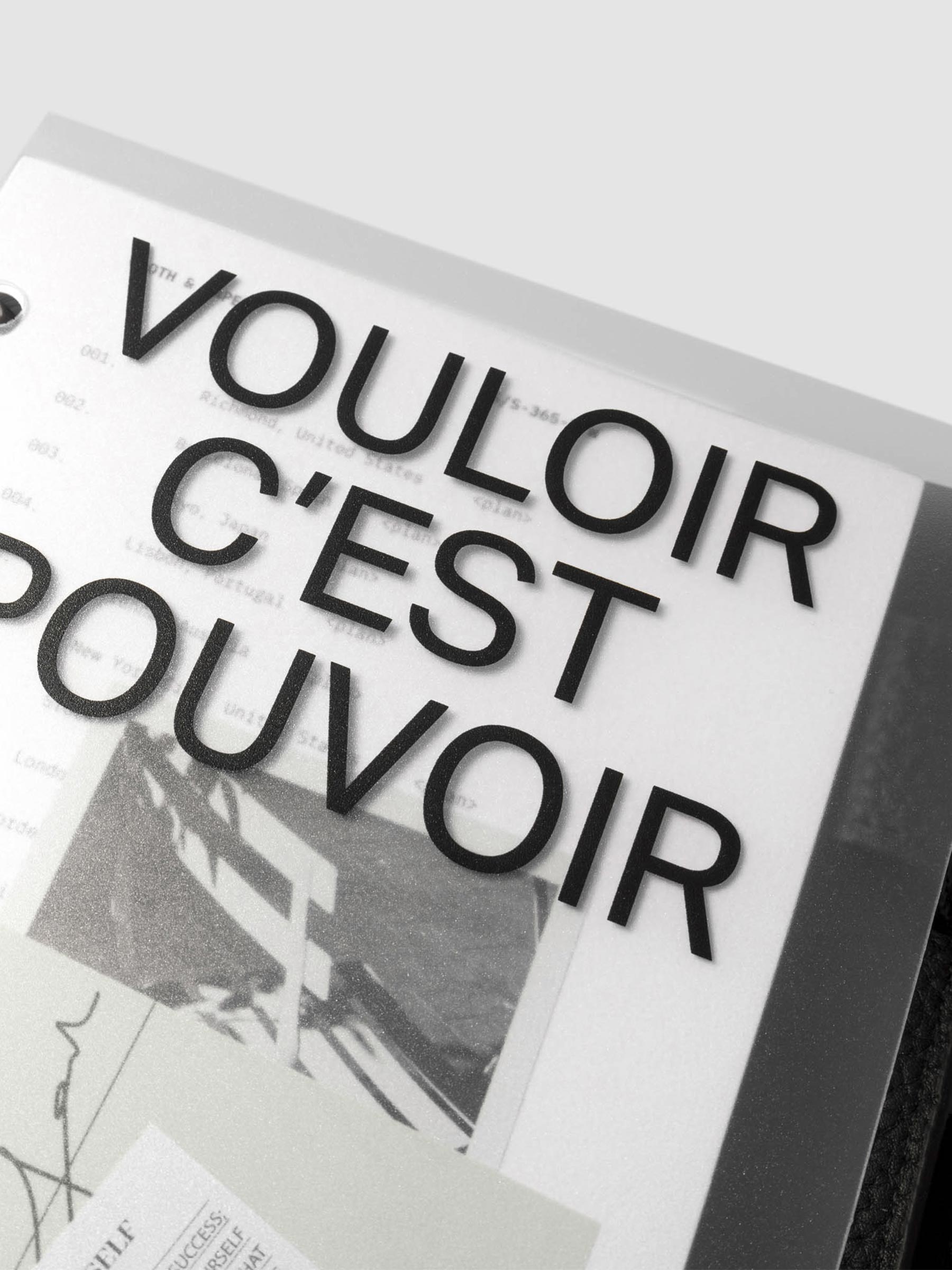 Close up image of the top half of the Moments Cover and Dashboard displayed in black agenda with silver rings.  The text reads Vouloir C'est Pouvoir. It is turned at a slight angle on a neutral background.