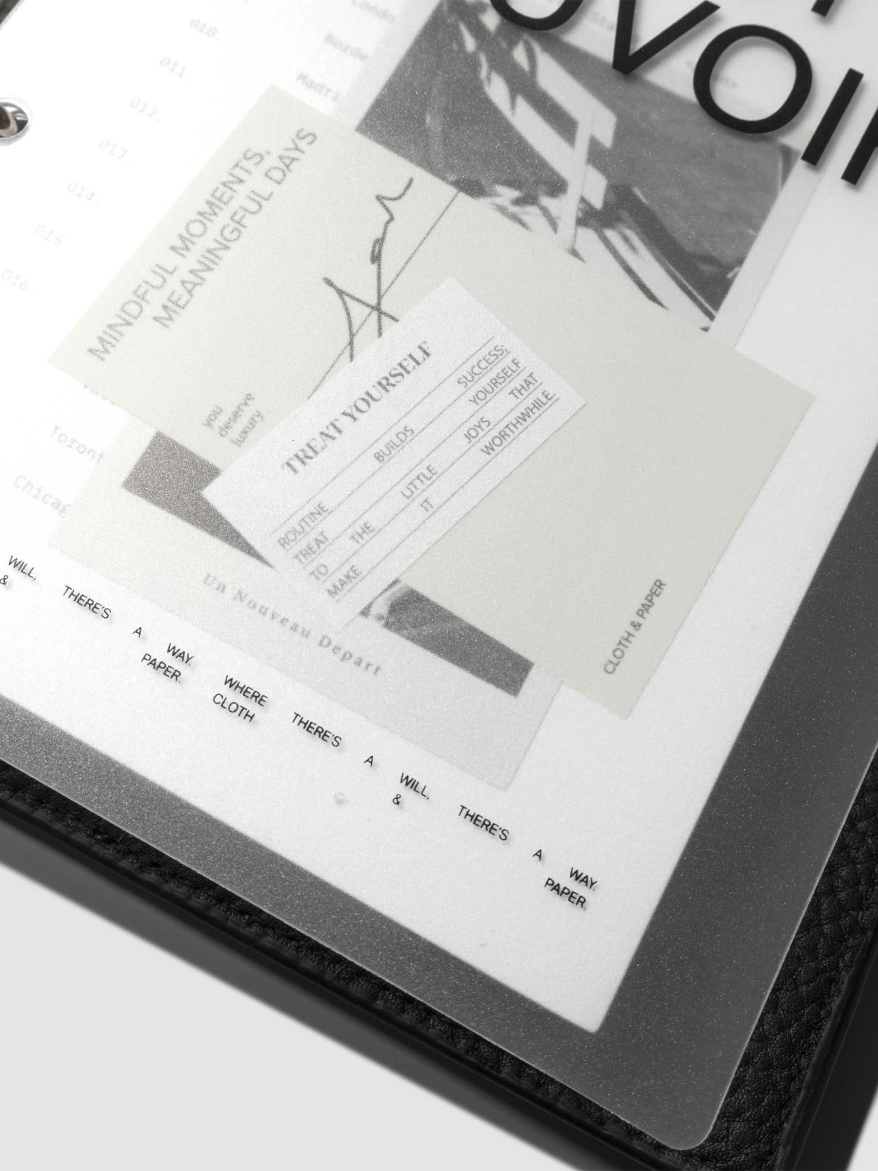 Close up image of the bottom half of the Moments Cover and Dashboard displayed in a black agenda with silver rings. It is turned at a slight angle on a neutral background.