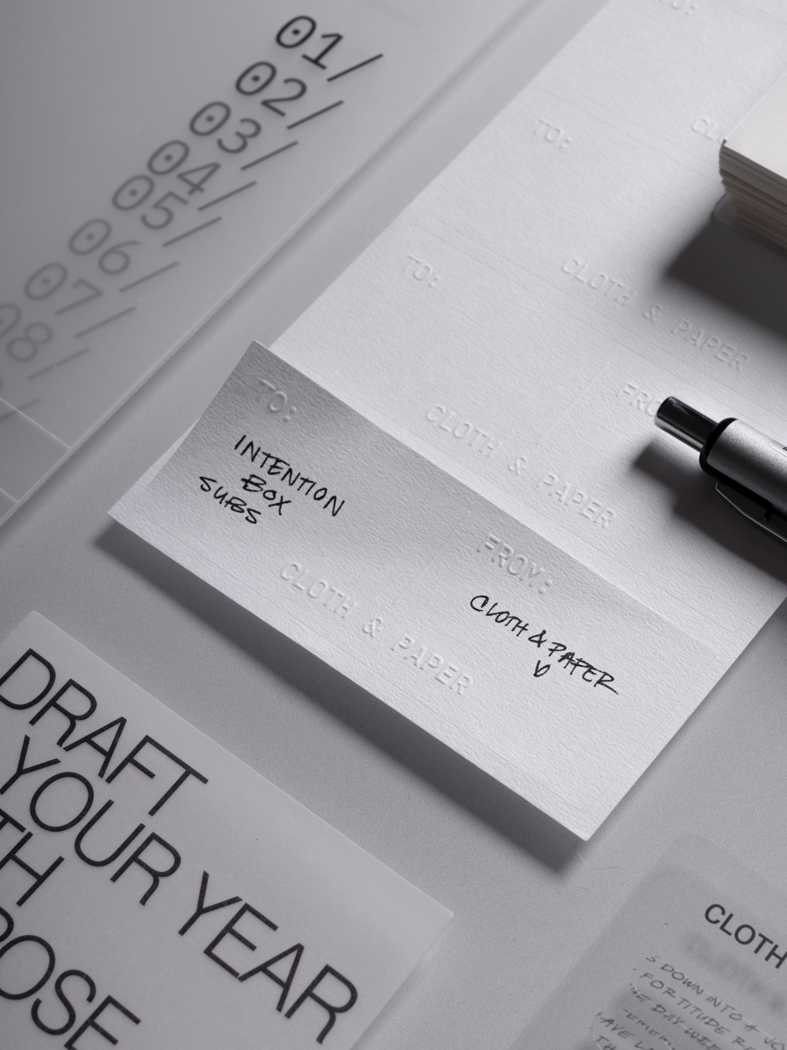 Label Planner Stickers | Gift Tag shown with handwritten text, slightly peeled away from the sticker sheet to show the embossed To, From, and Cloth & Paper text.