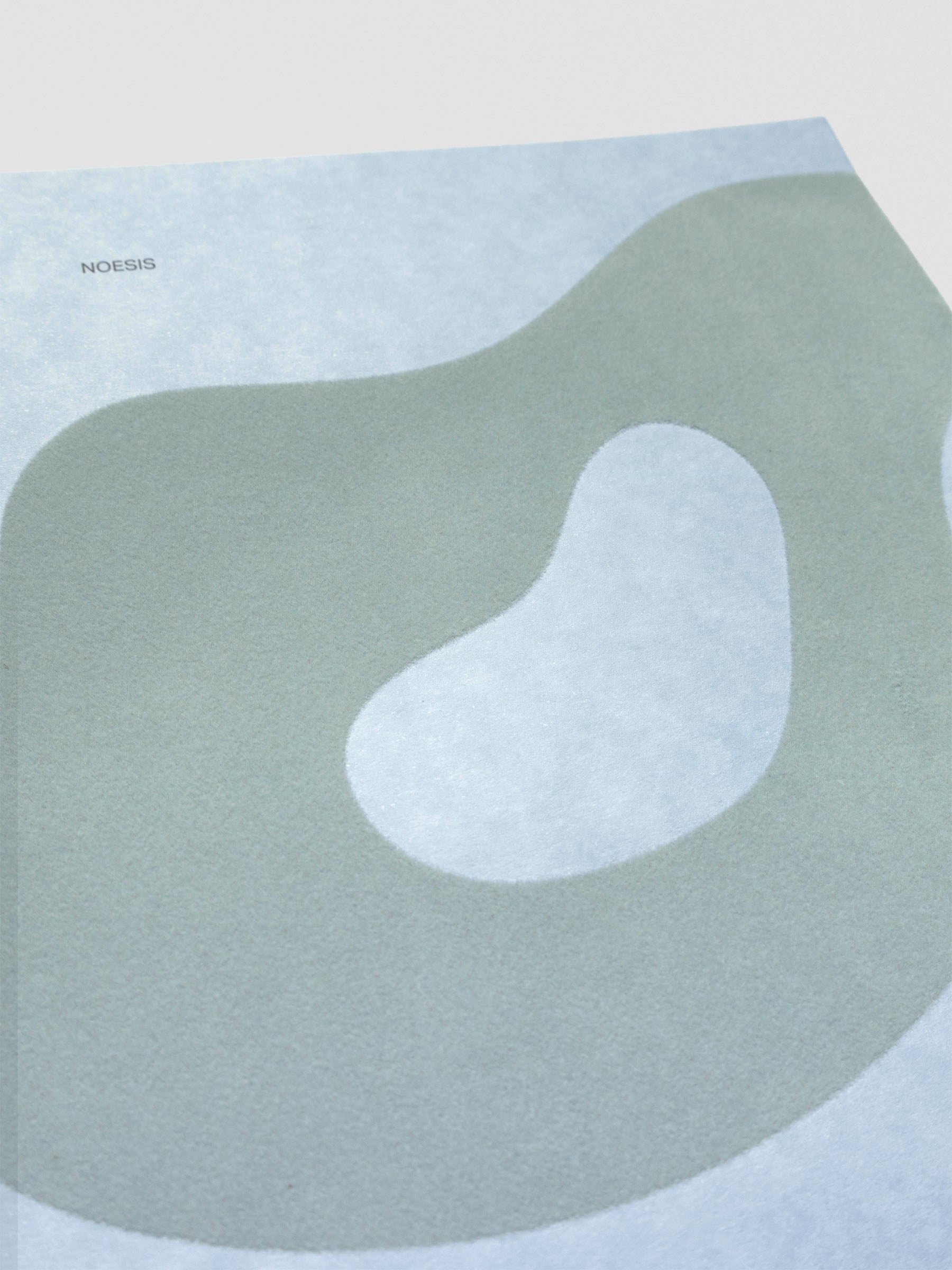 Close up of the blue-green flocking on blue speckled cardstock with the text 'Noesis'.