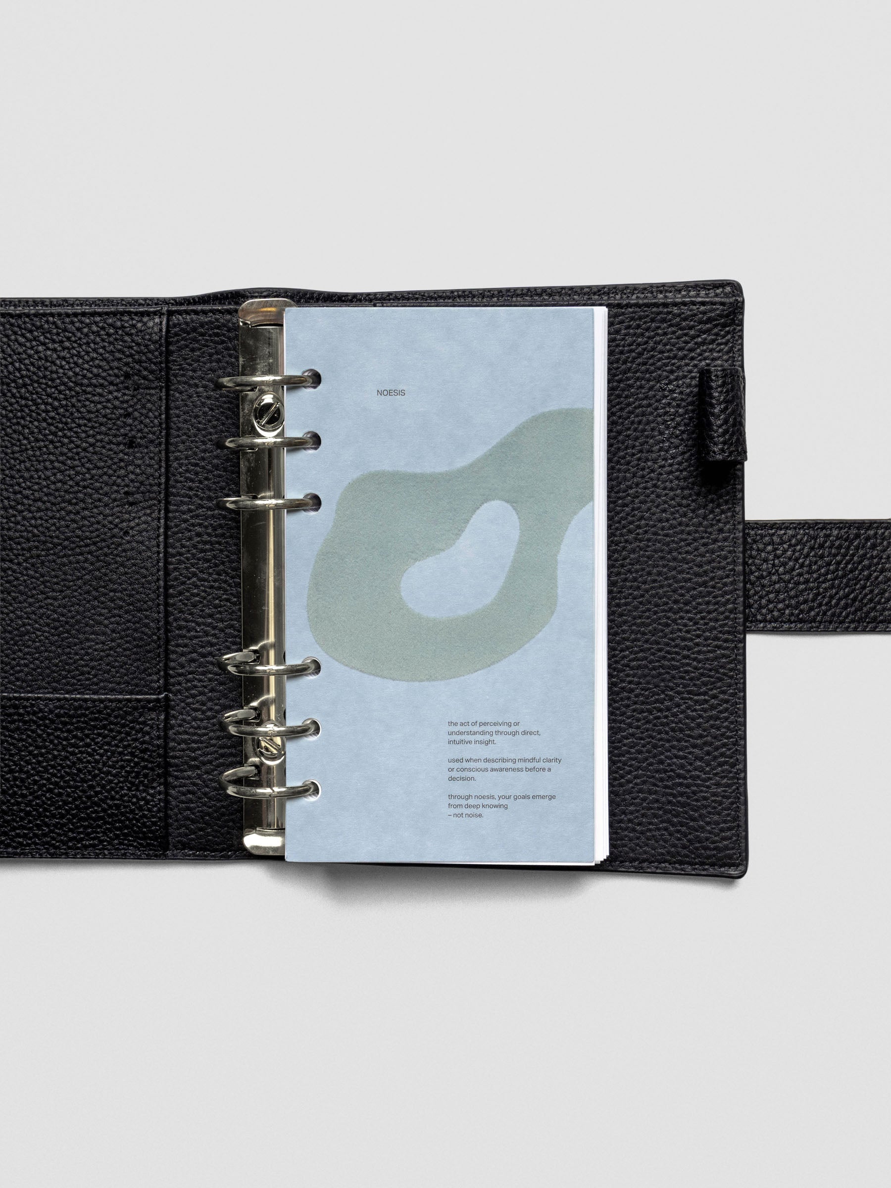 Blue speckle cardstock planner dashboard with organic shape design flocked in blue-green with text design shown in Personal size in a ring bound leather cover.