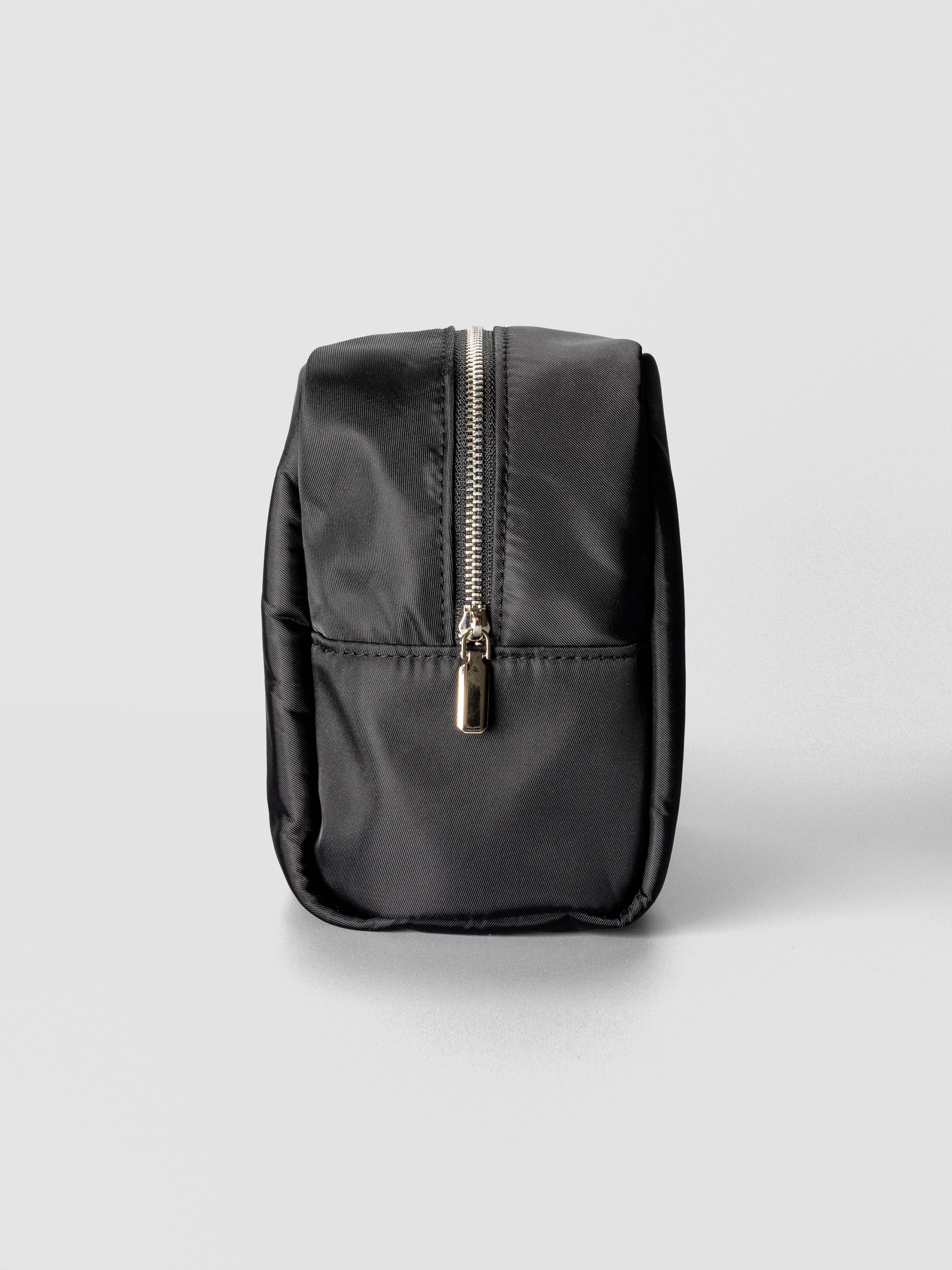 A sleek black nylon pouch with a structured rectangular shape and a silver zipper running down the center.