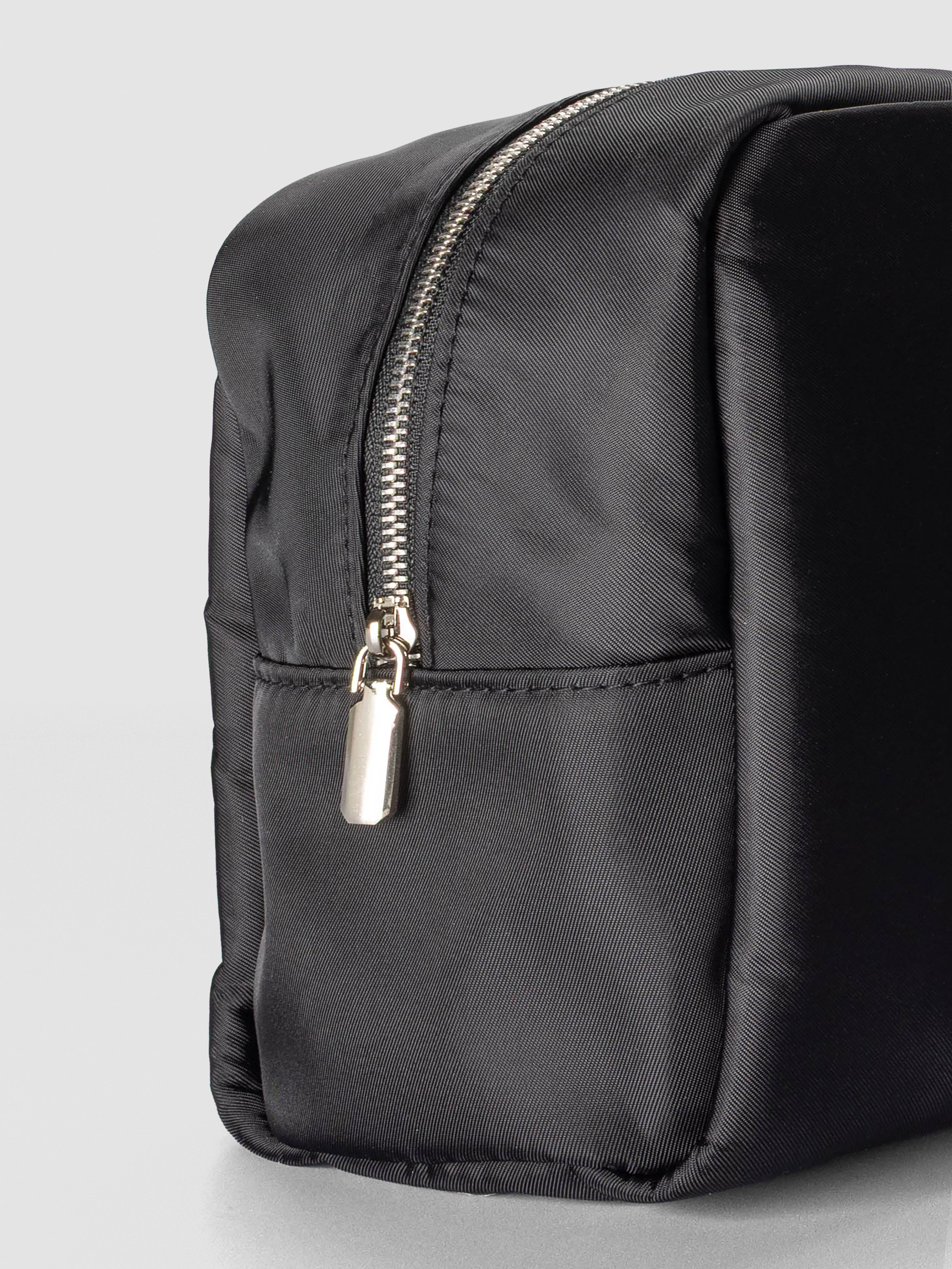 Close-up of the pouch showing its slightly padded structure, smooth nylon texture, and silver zipper detail.