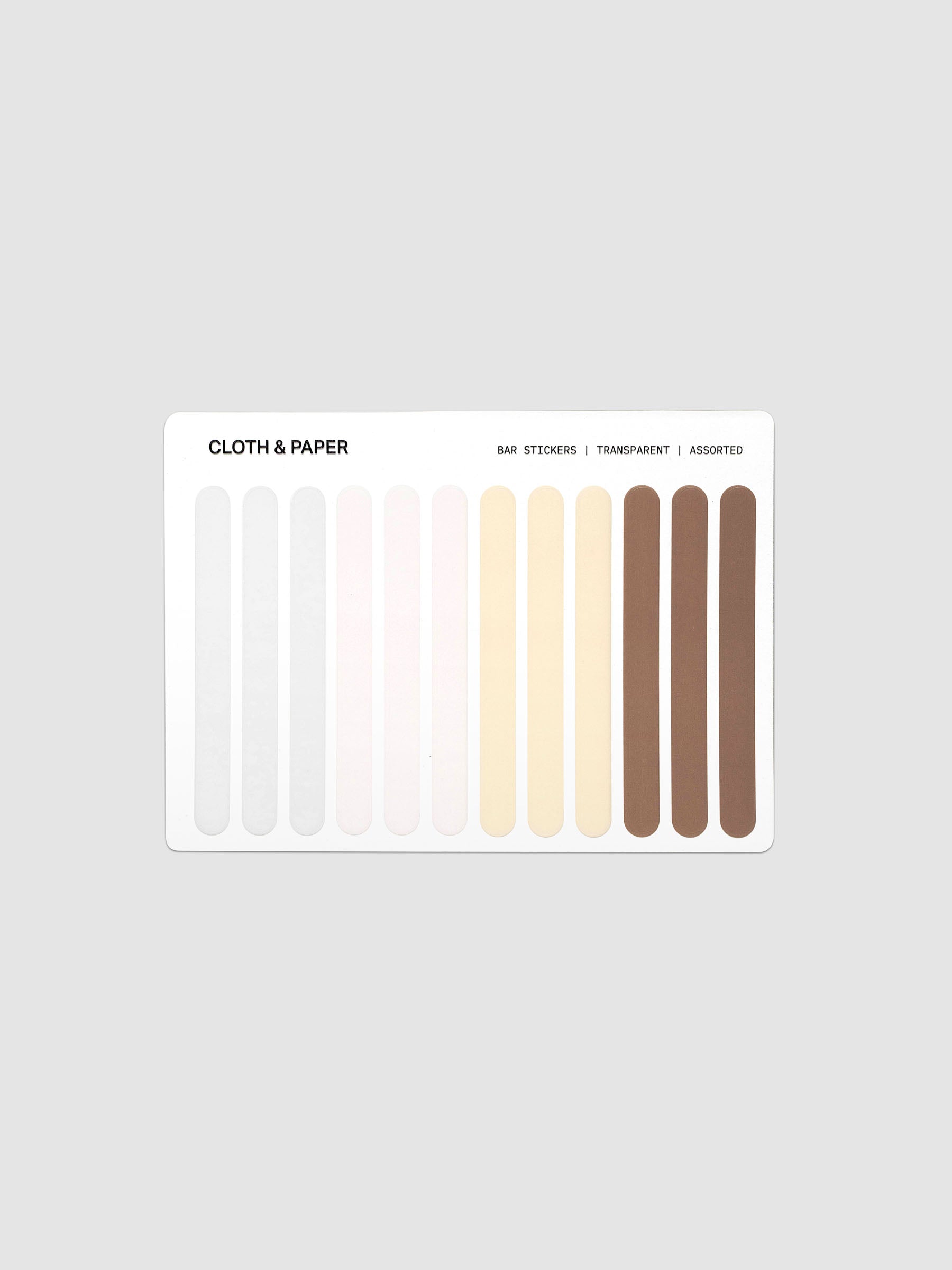 A sheet of adhesive color strips labeled 'CLOTH & PAPER' with text reading 'BAR STICKERS | TRANSPARENT | ADDED', showing multiple vertical color samples in pale gray, white, cream, beige, tan, and brown tones on a light gray background.