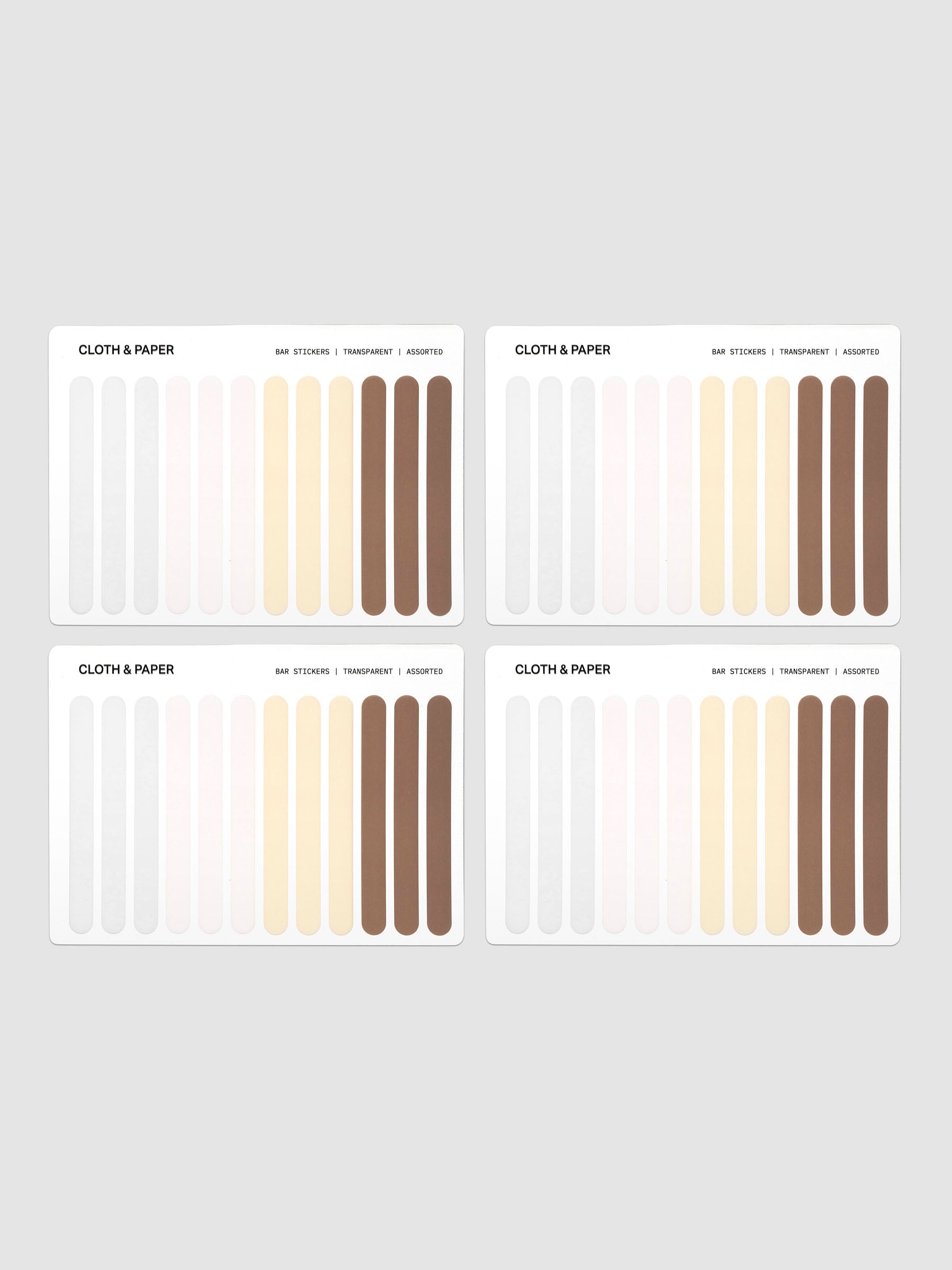 Four identical swatch cards arranged in a 2x2 grid on a light gray background. Each card shows vertical color strips in white, pale pink, cream, beige, and brown, with small text reading CLOTH & PAPER and additional tiny labels.
