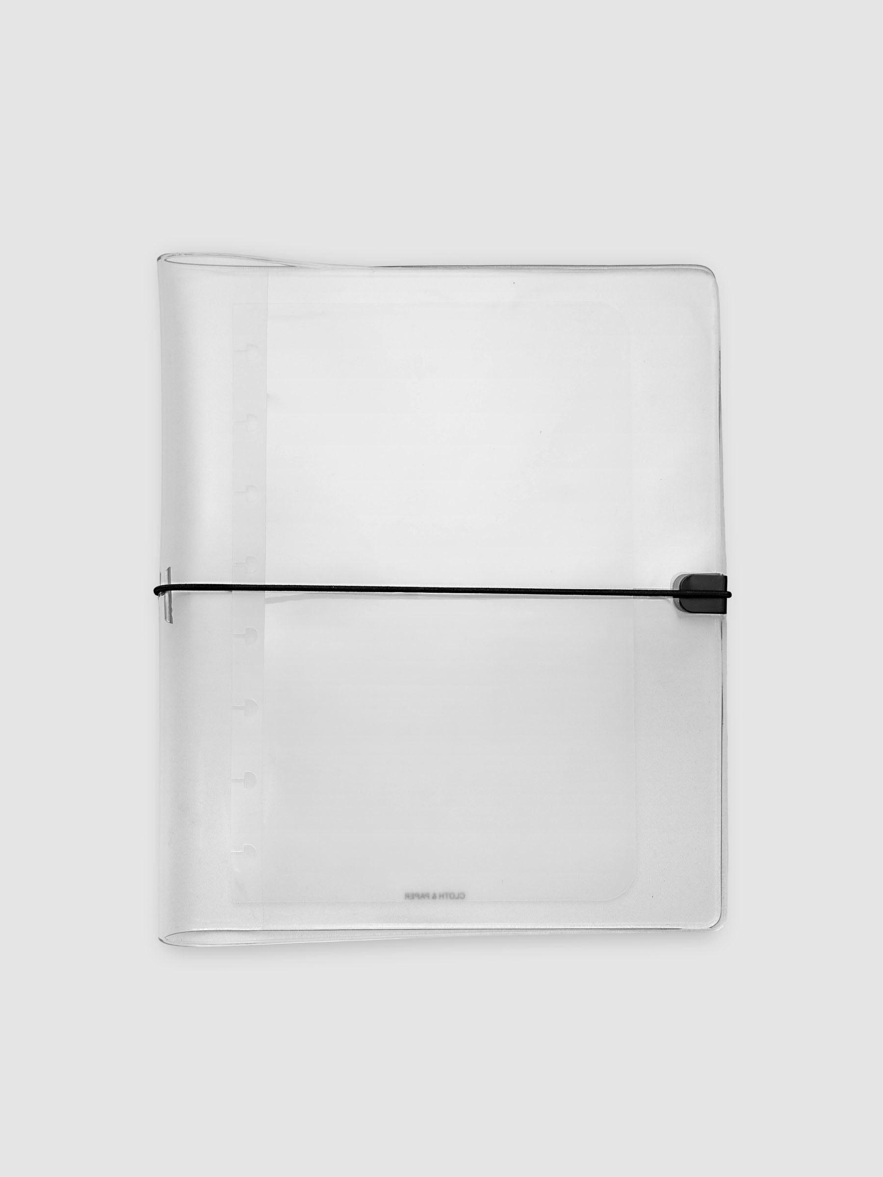 A clear plastic large notebook cover with a black elastic closure band, closed, against a light gray background.
