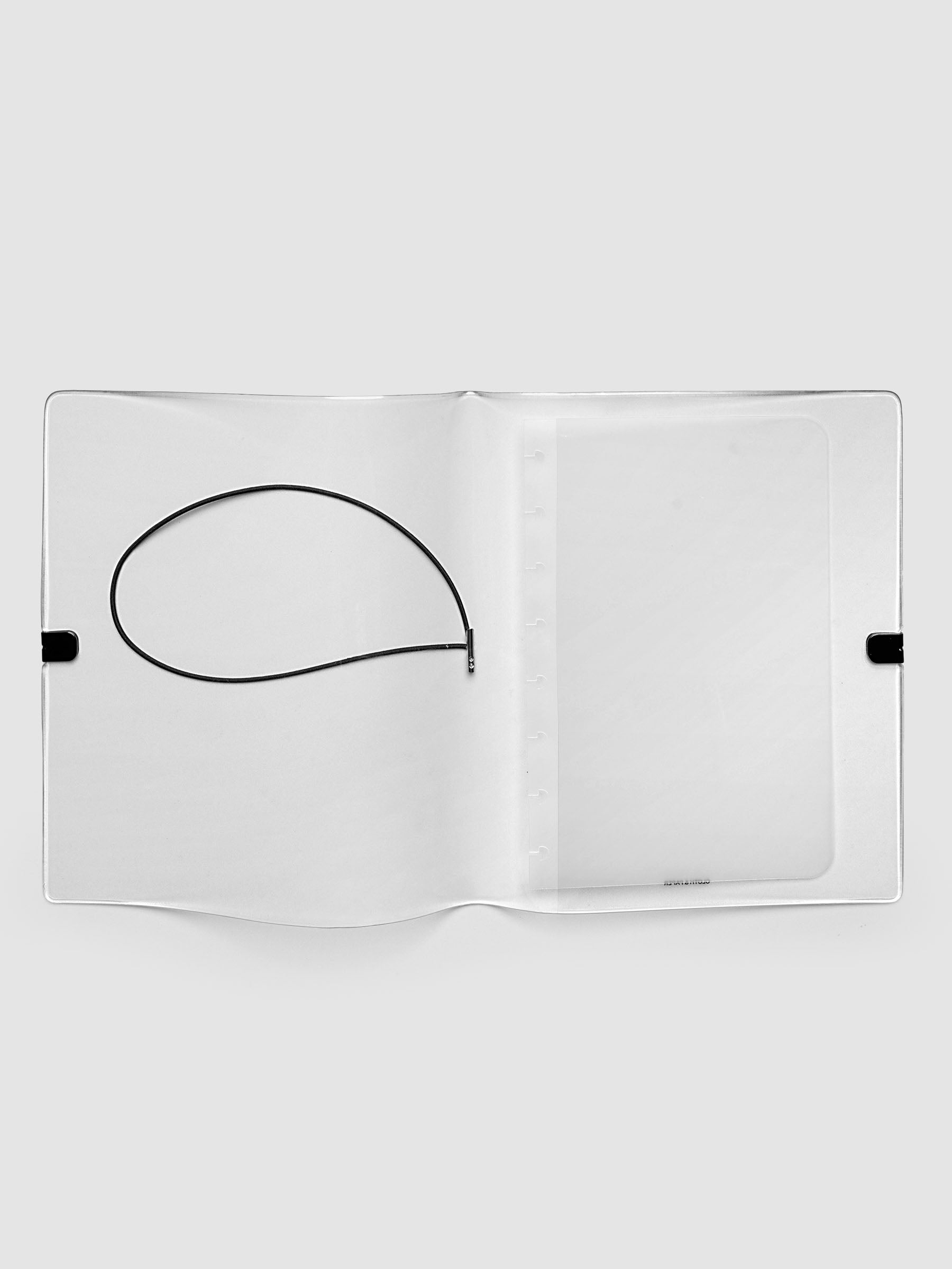 A clear plastic notebook cover with a black elastic closure band, opened and laid flat, against a light gray background.