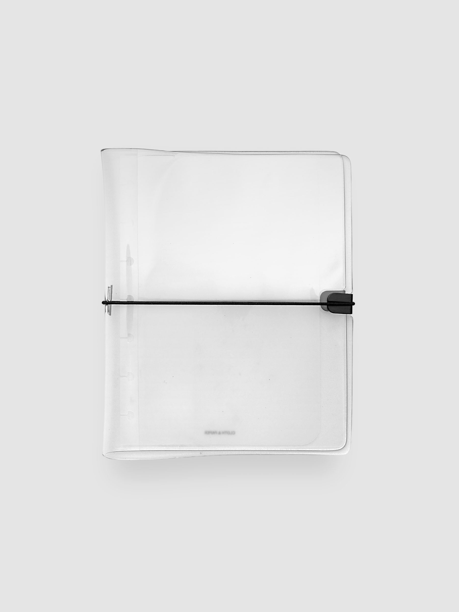 A clear plastic notebook cover with a black elastic closure band, shown flat against a light gray background.