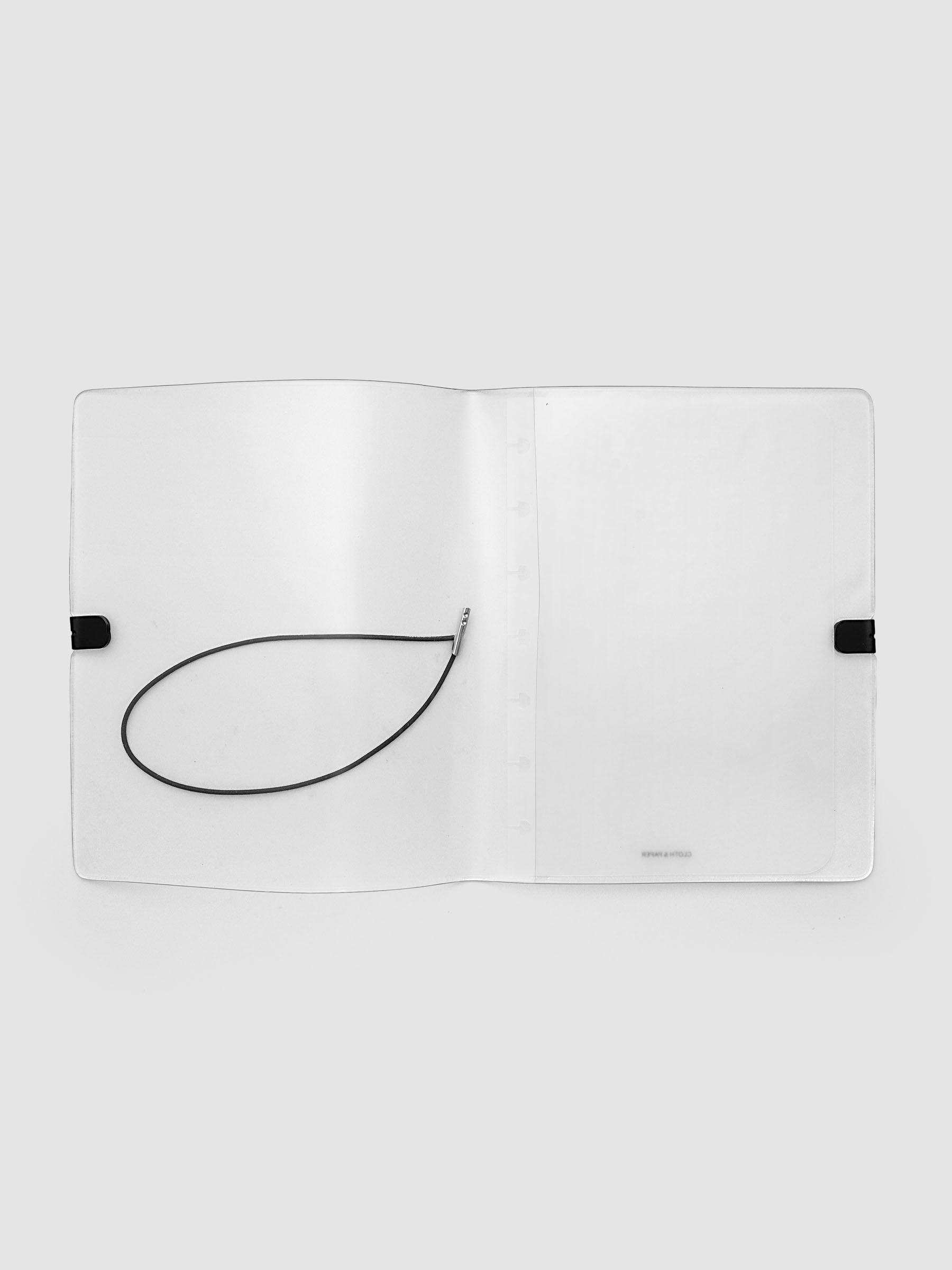 A clear plastic notebook cover with a black elastic closure band, opened flat against a light gray background.
