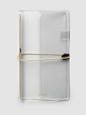 A clear acrylic notebook cover with a beige metal band closure, shown on a light gray background.