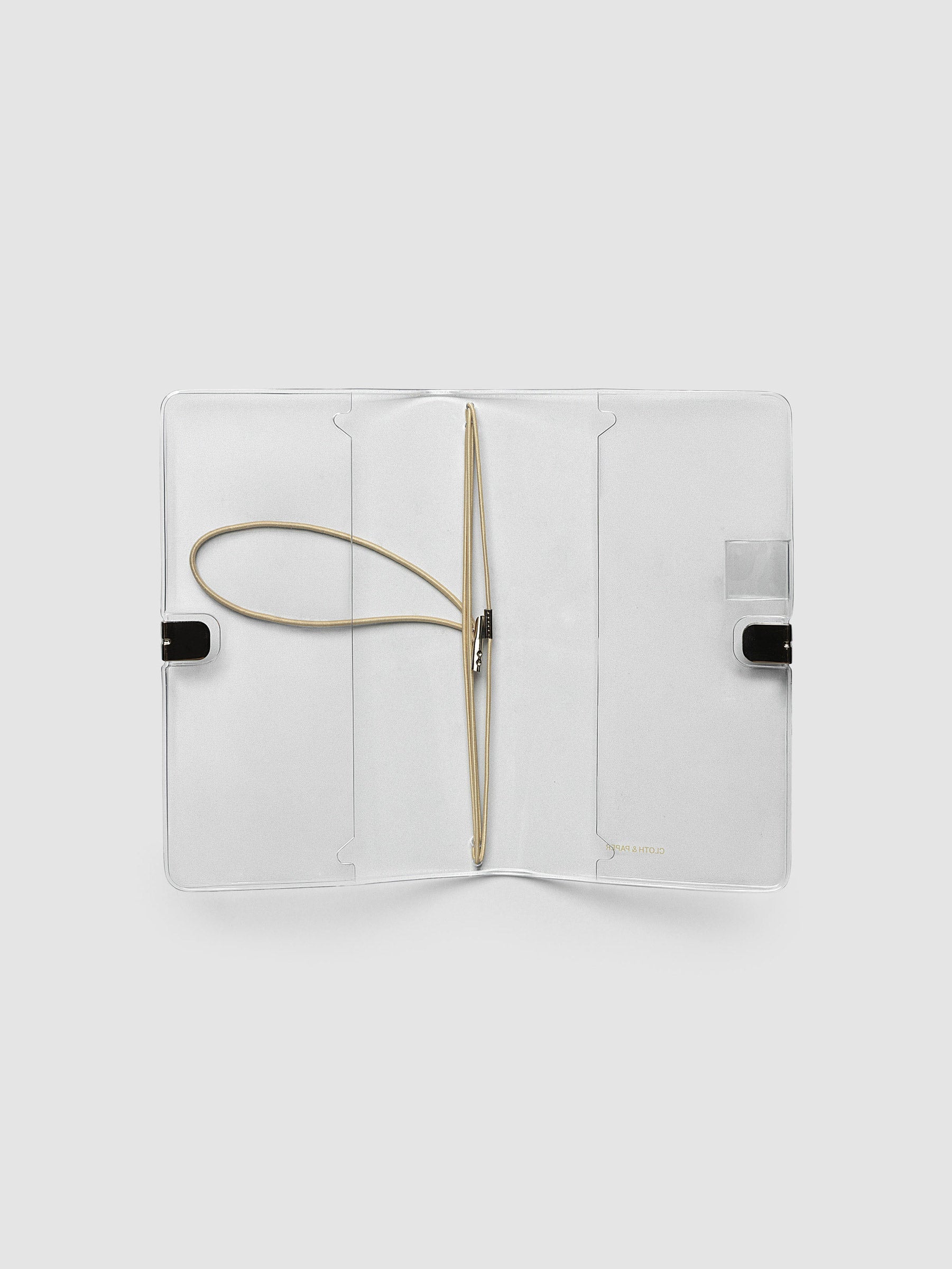 Clear Vinyl Travel Notebook Cover in Pocket Plus shown open flat with the interior pockets and bungee strings visible.