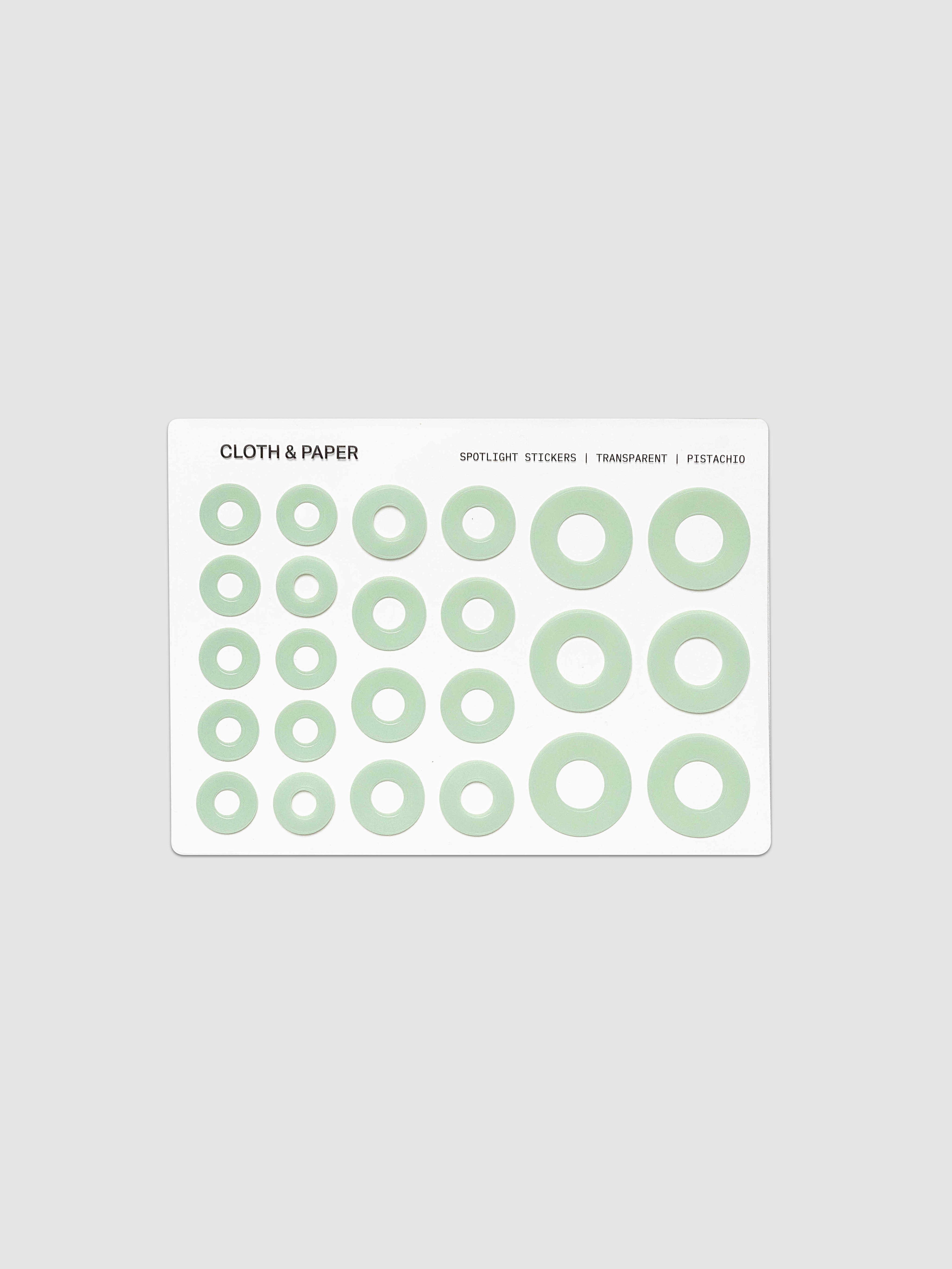 One sheet of circular stickers in varying sizes, featuring a light sage green ring design on a white backing card, set against a solid light gray background.