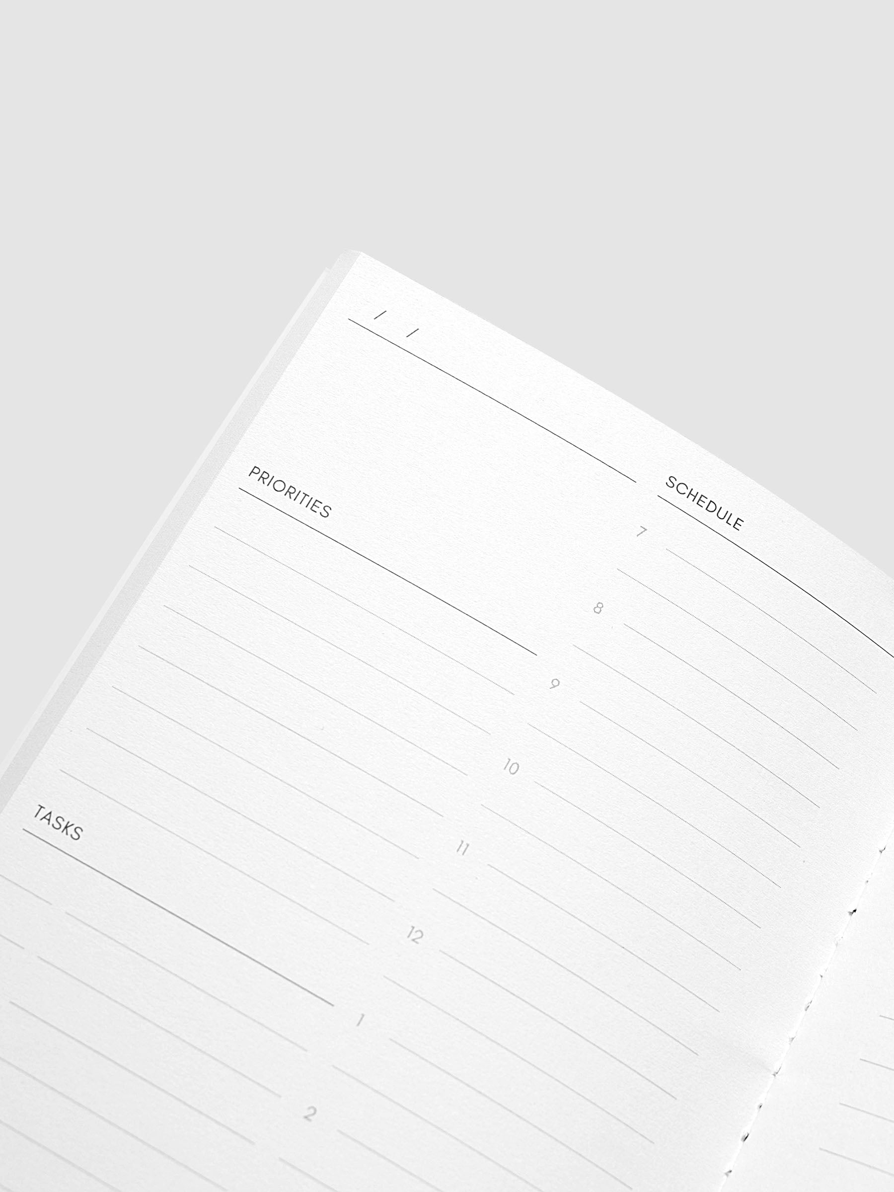 An open planner or notebook page showing a daily planner layout with sections for priorities, schedule, and tasks, photographed on a light gray background.