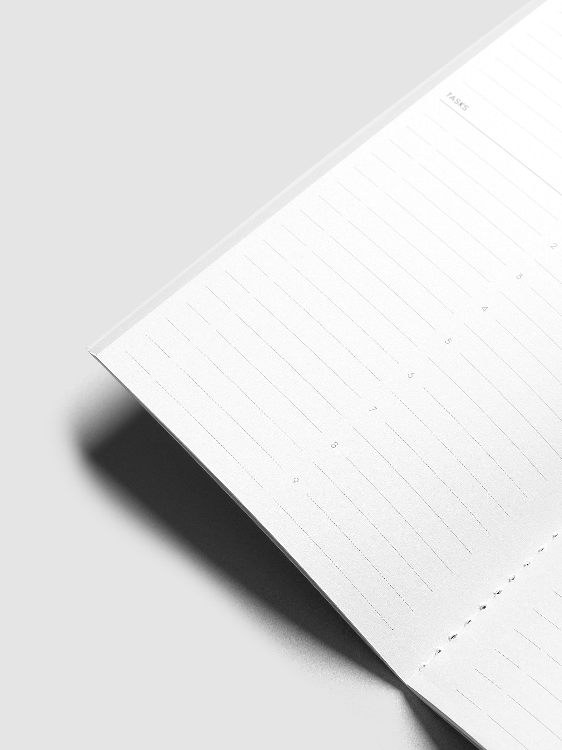 A close-up of a white lined notebook page, photographed on a light gray background with a soft shadow.