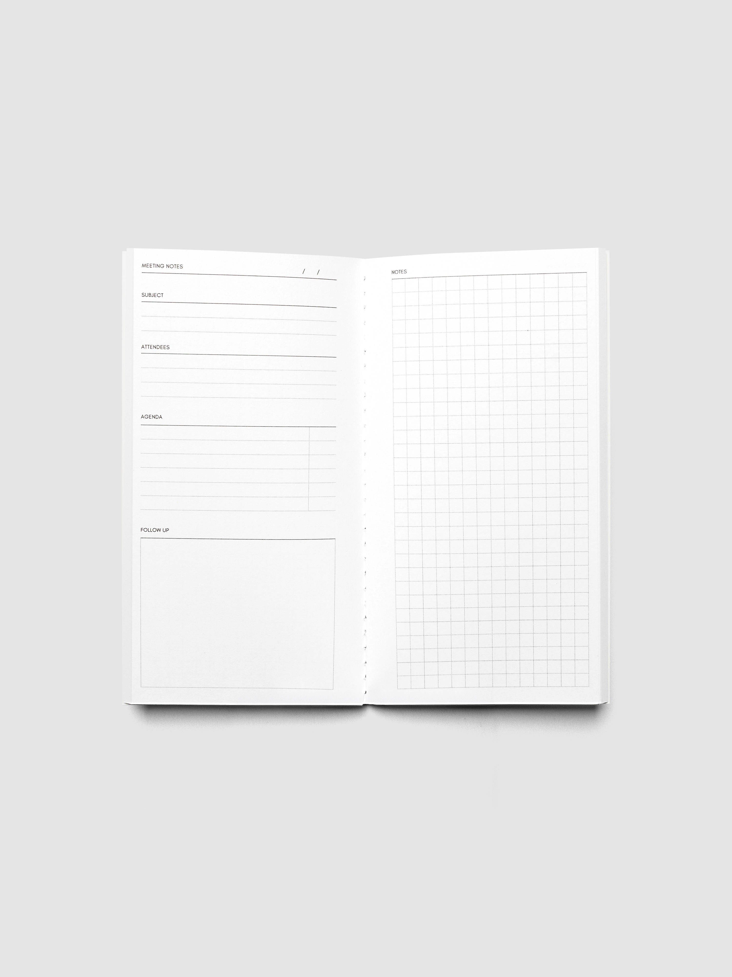 An open white planner or notebook showing lined note pages on the left and a grid graph page on the right, photographed on a light gray background.