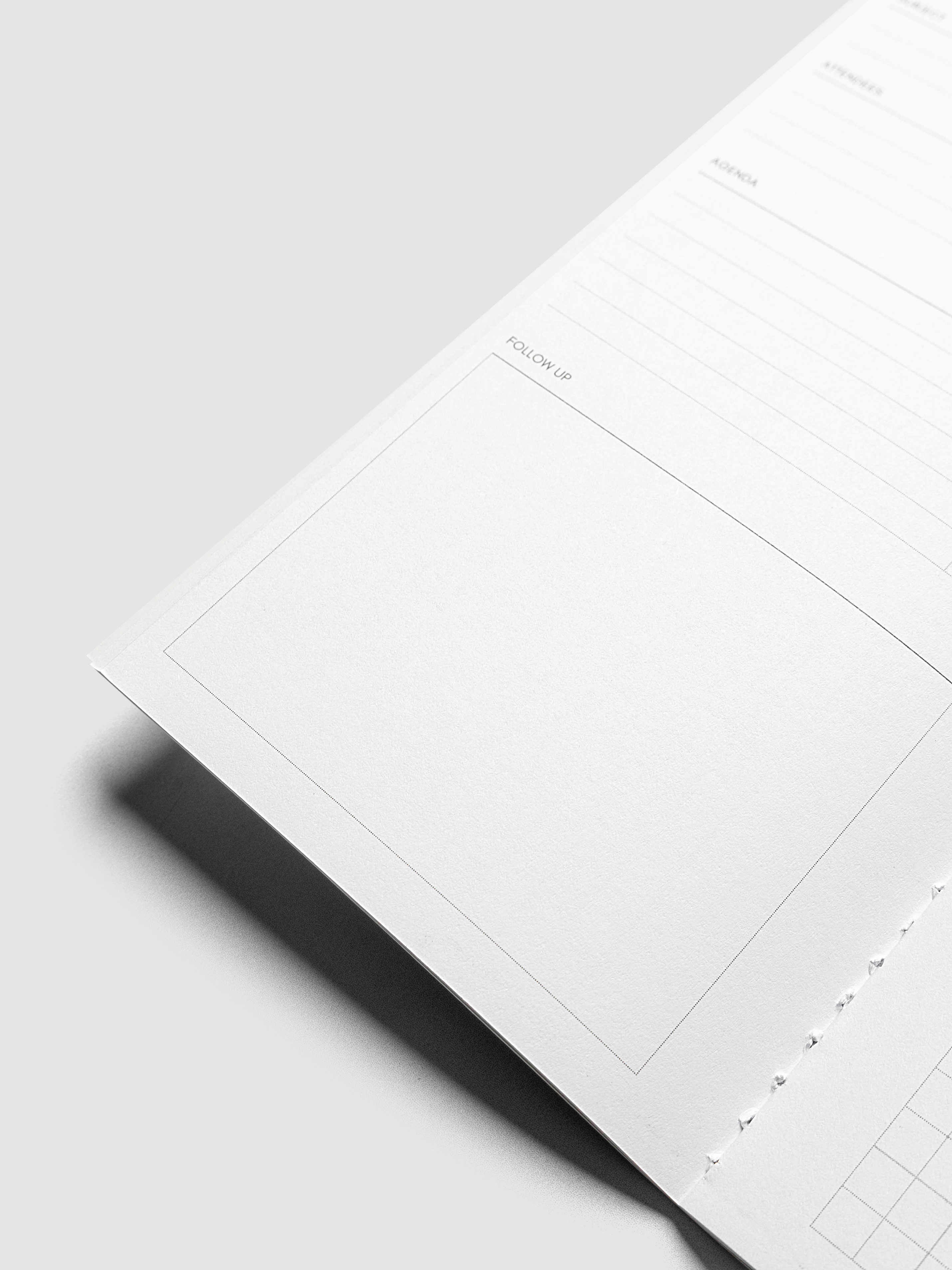 A close-up of a white notebook insert with printed lines and photographed on a light gray background with a soft shadow.