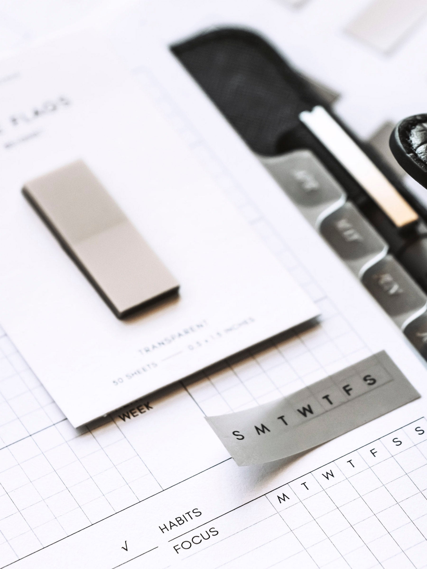 Close up on printed page flag in use inside a planner. A pad of page flags sits on the page next to it.