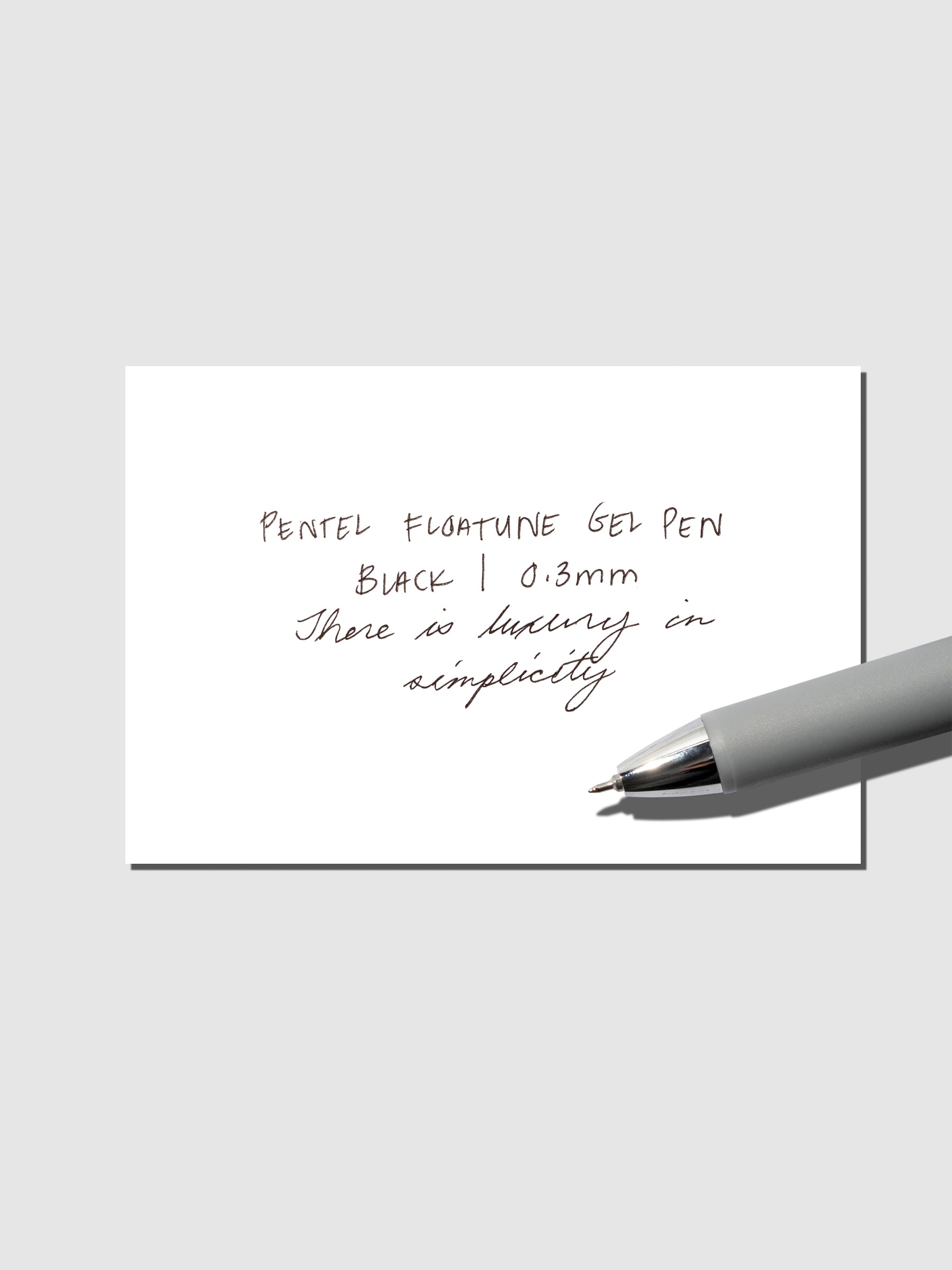 Pentel Floatune Gel Pen 0.3mm black ink. Pen resting on pen test sheet displaying writing sample.