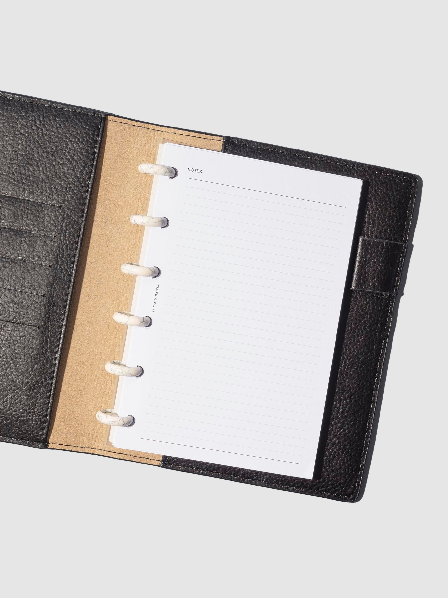White 0.75 inch discs in use inside a leather planner. Size shown is CP Petite.
