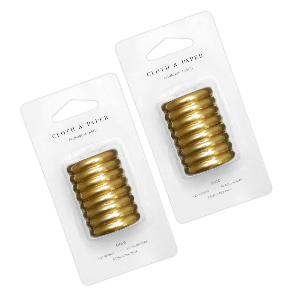 Planner Discs, 1.25 Inch, Gold, Cloth and Paper. 2 blister packs of gold aluminum discs side by side, turned slightly to the left against a white background.