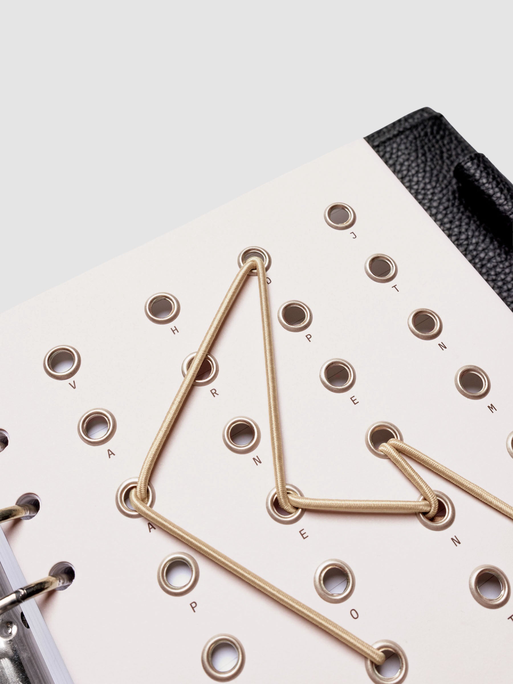 Cadence Dashboard with grommets and string on beige cardstock shown close up in a 6-ring planner.