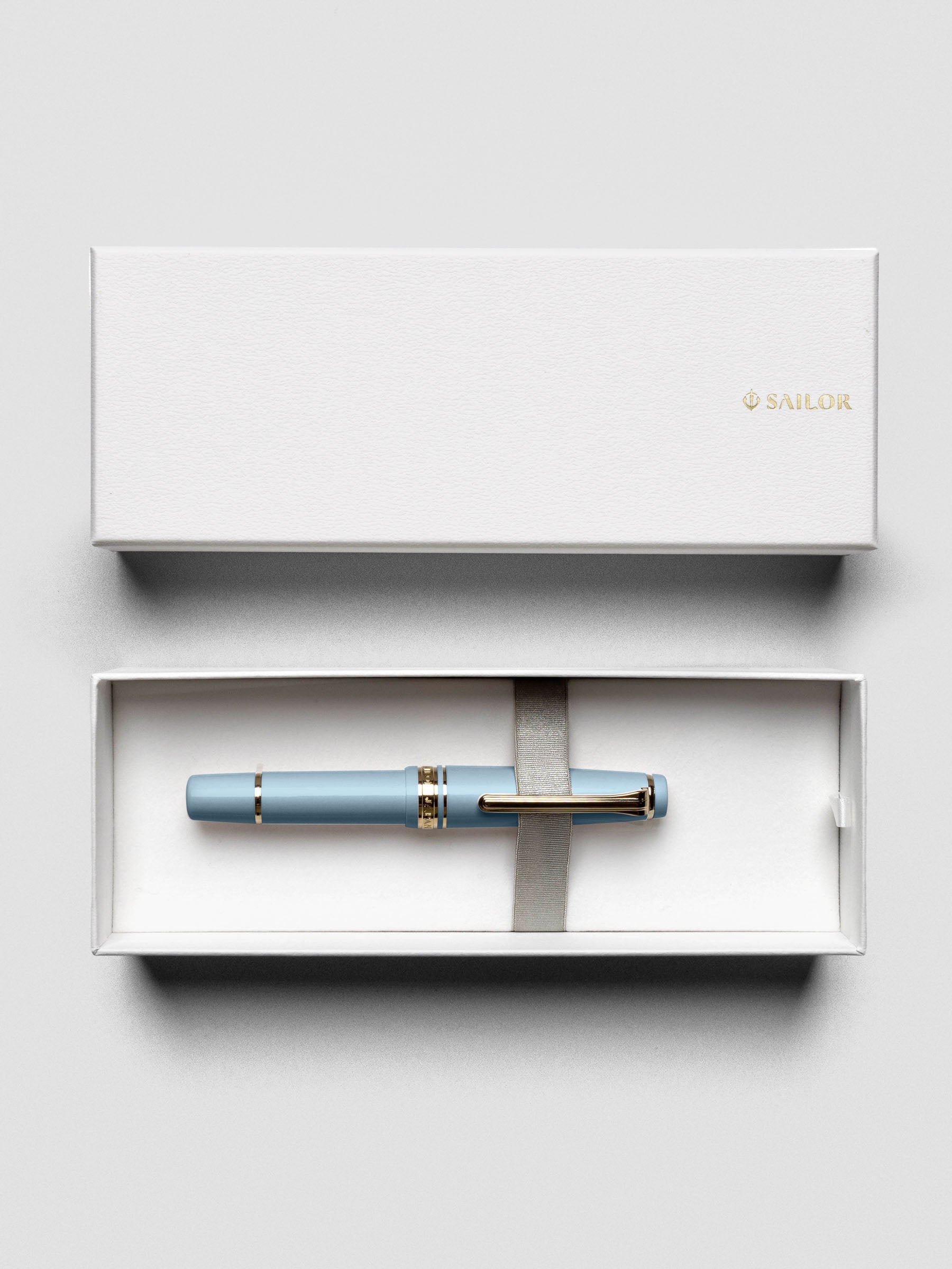 Flat lay of Sailor Pro Gear Slim Mini Fountain Pen in Ayur Blue with cap beside barrel.