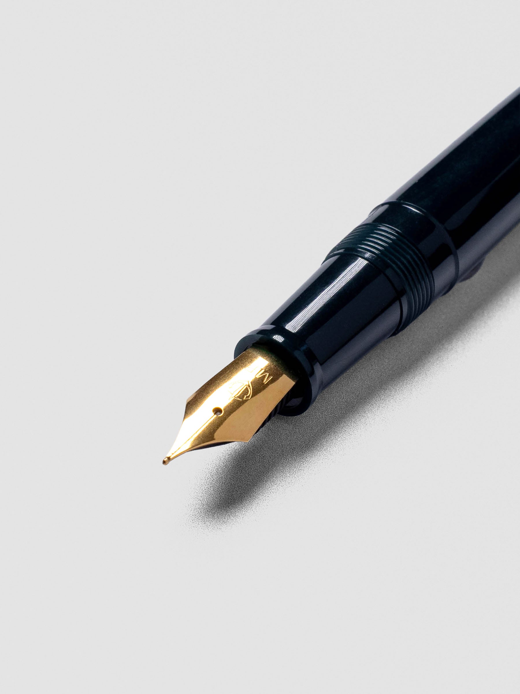 Sailor Recle Fountain Pen Medium in Teal Green placed inside an open notebook.