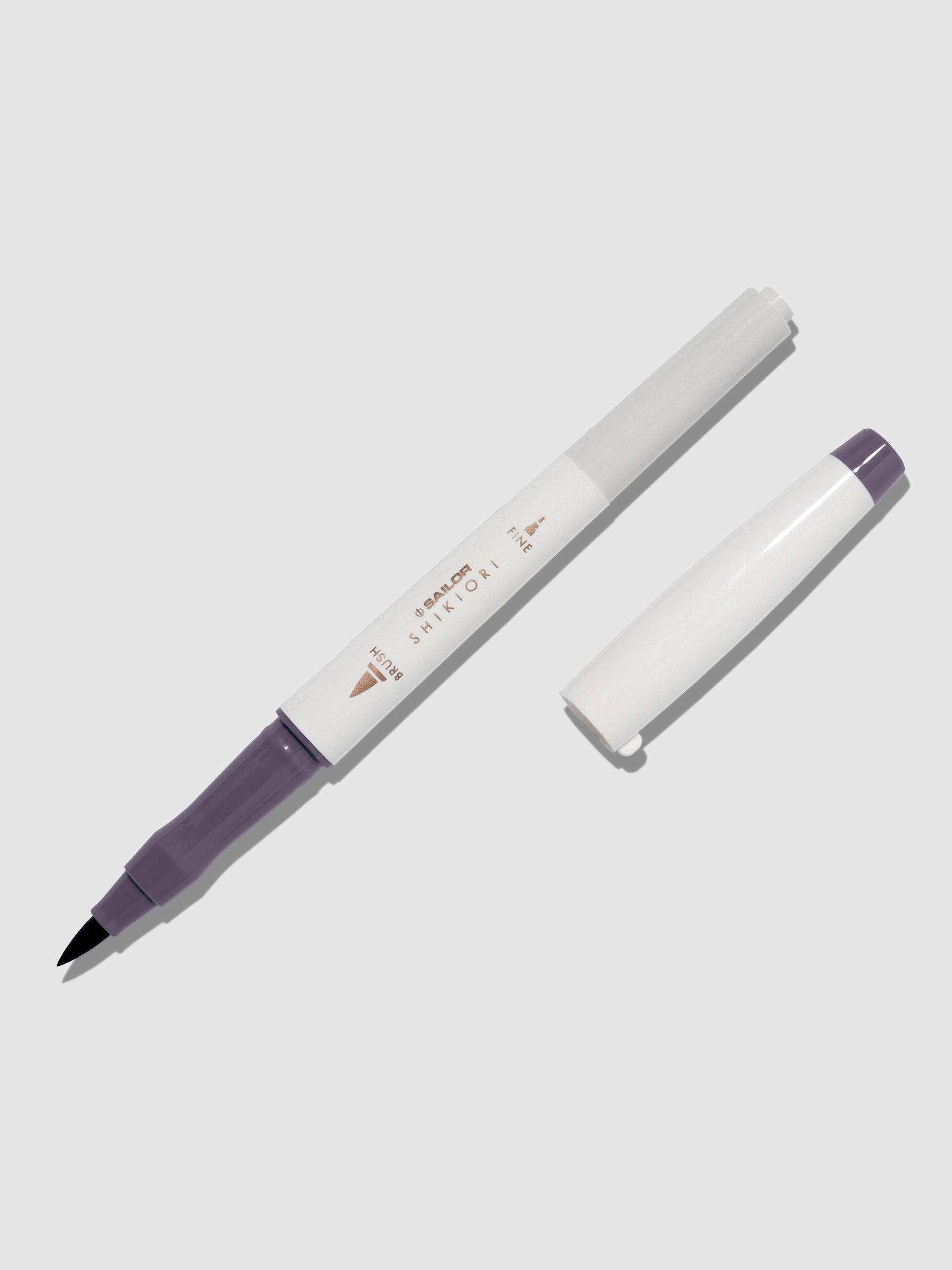 Brush pen displayed on a neutral background. It is uncapped with its brush nib exposed, and the cap lying parallel to the marker. Color pictured is Chushu. 