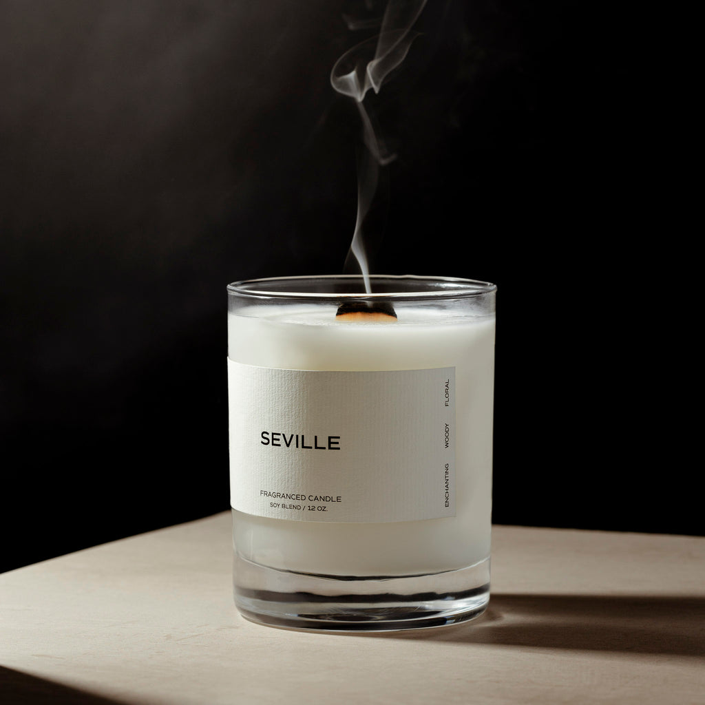A spoiler image from our Spring 2024 Aesthete Box.  The Seville Candle sitting on a table against a black background.  There is smoke rising from the candle after it has been extinguished.