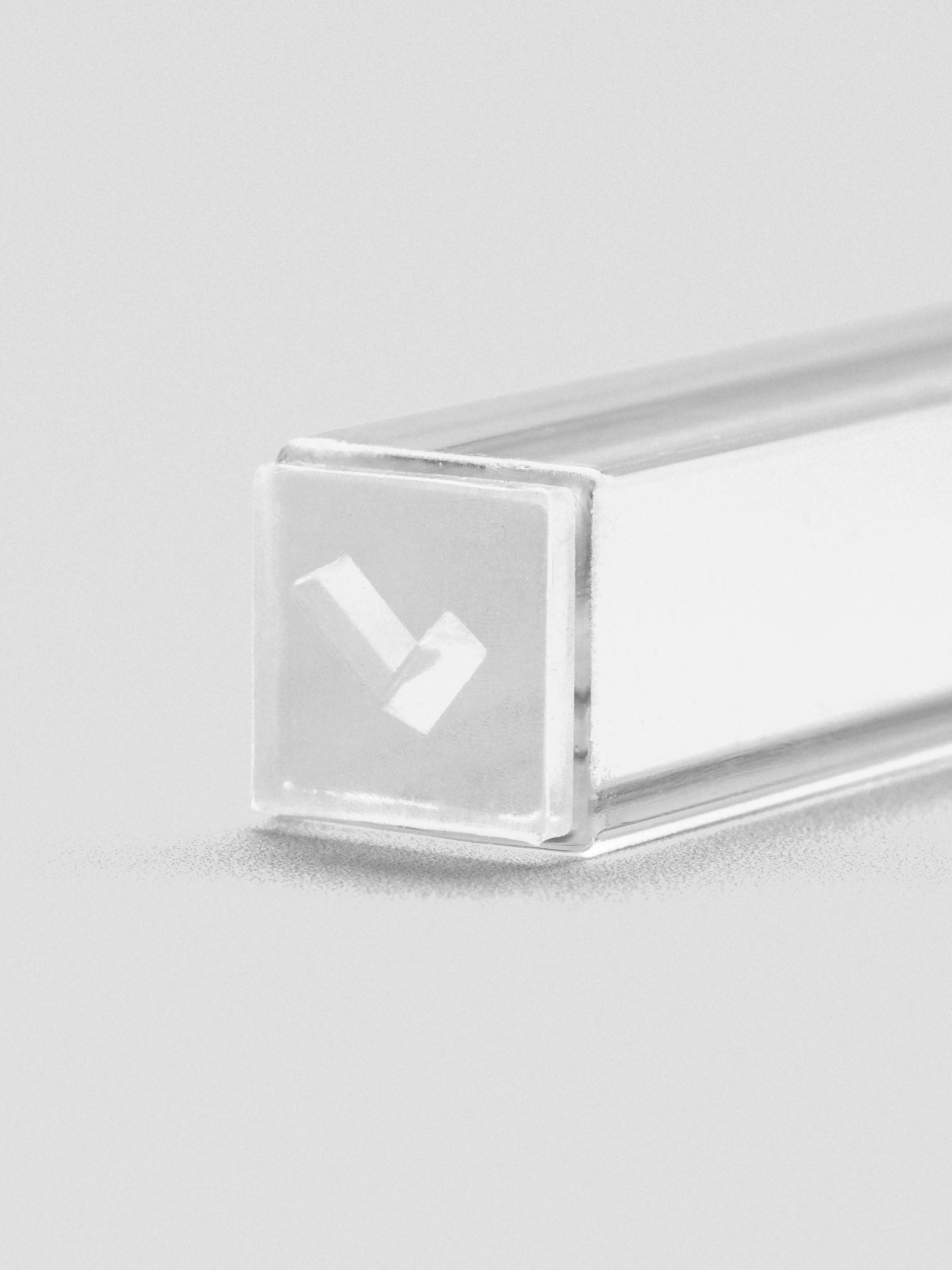 Close-up of stamp stick end showing an engraved checkmark icon.