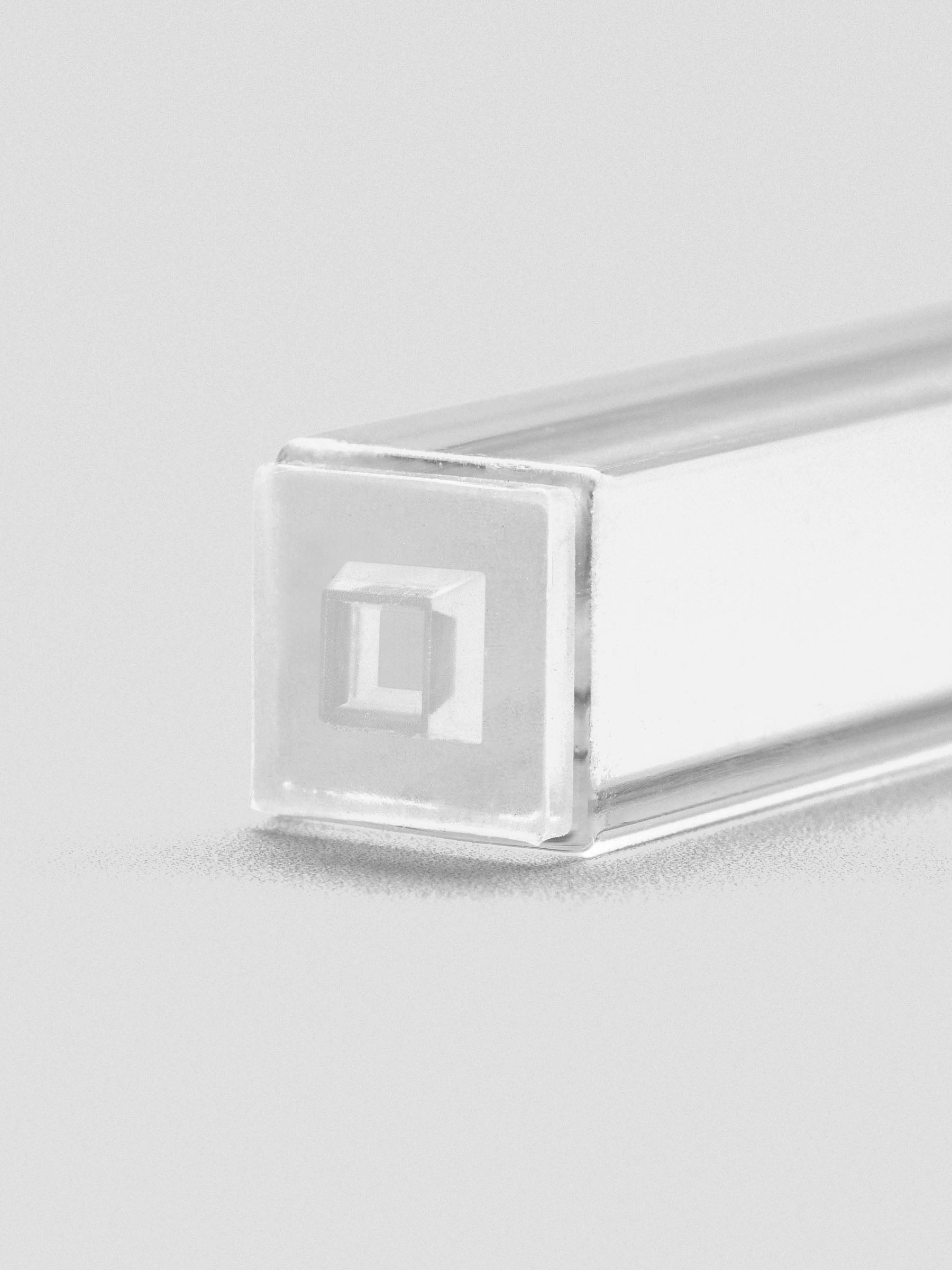 Close-up of stamp stick end with an engraved outlined square icon.