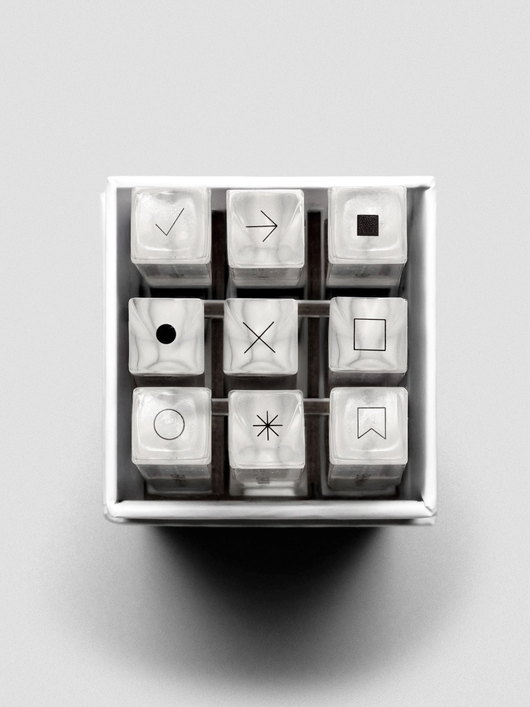 Overhead view of the nine stamp sticks arranged in a 3x3 grid inside the box, icons visible on top.