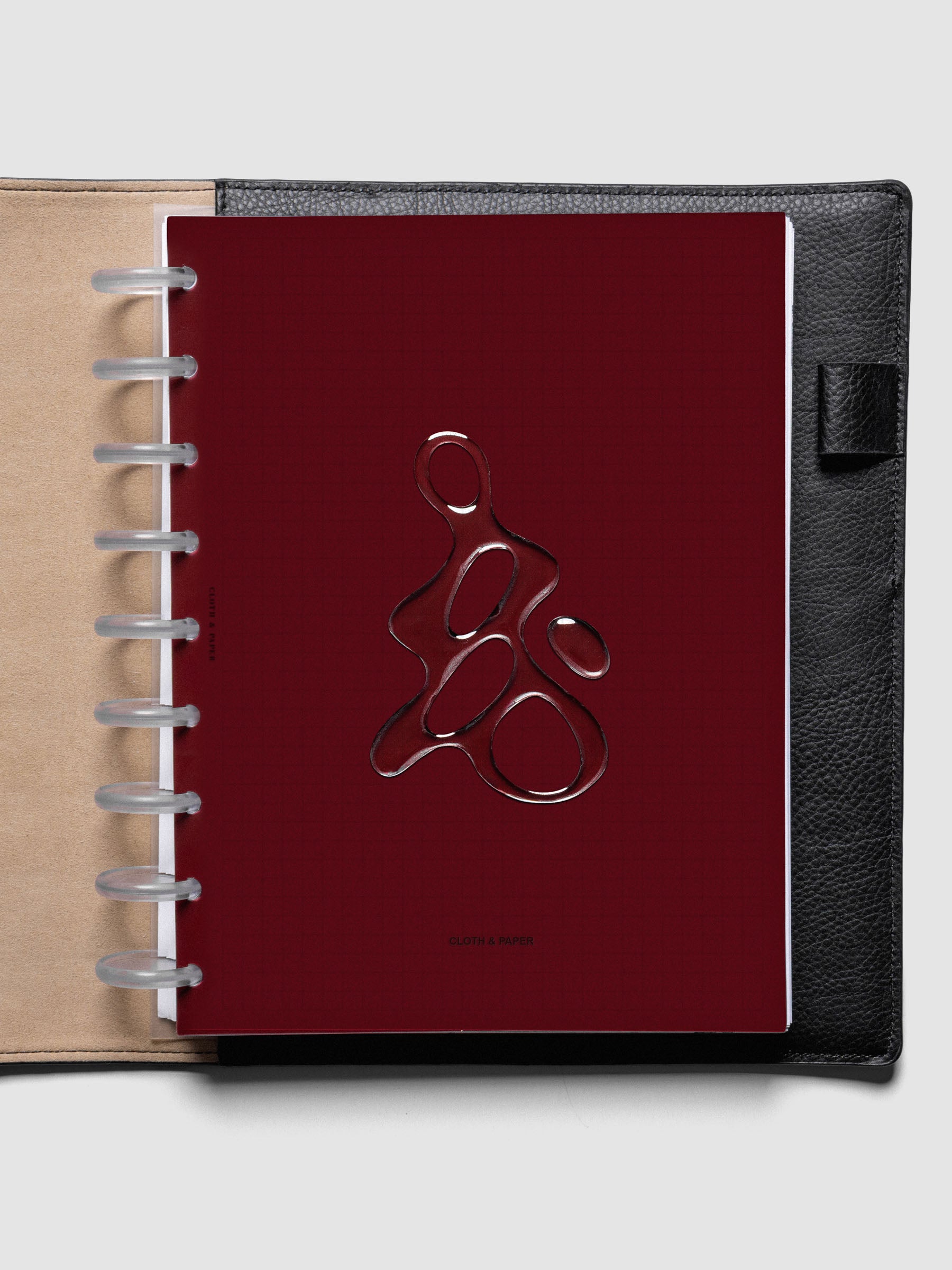 Dark red, semi-transparent, and glossy plastic planner dashboard with organic raised shape design in size HP Classic shown discbound in a black leather folio.