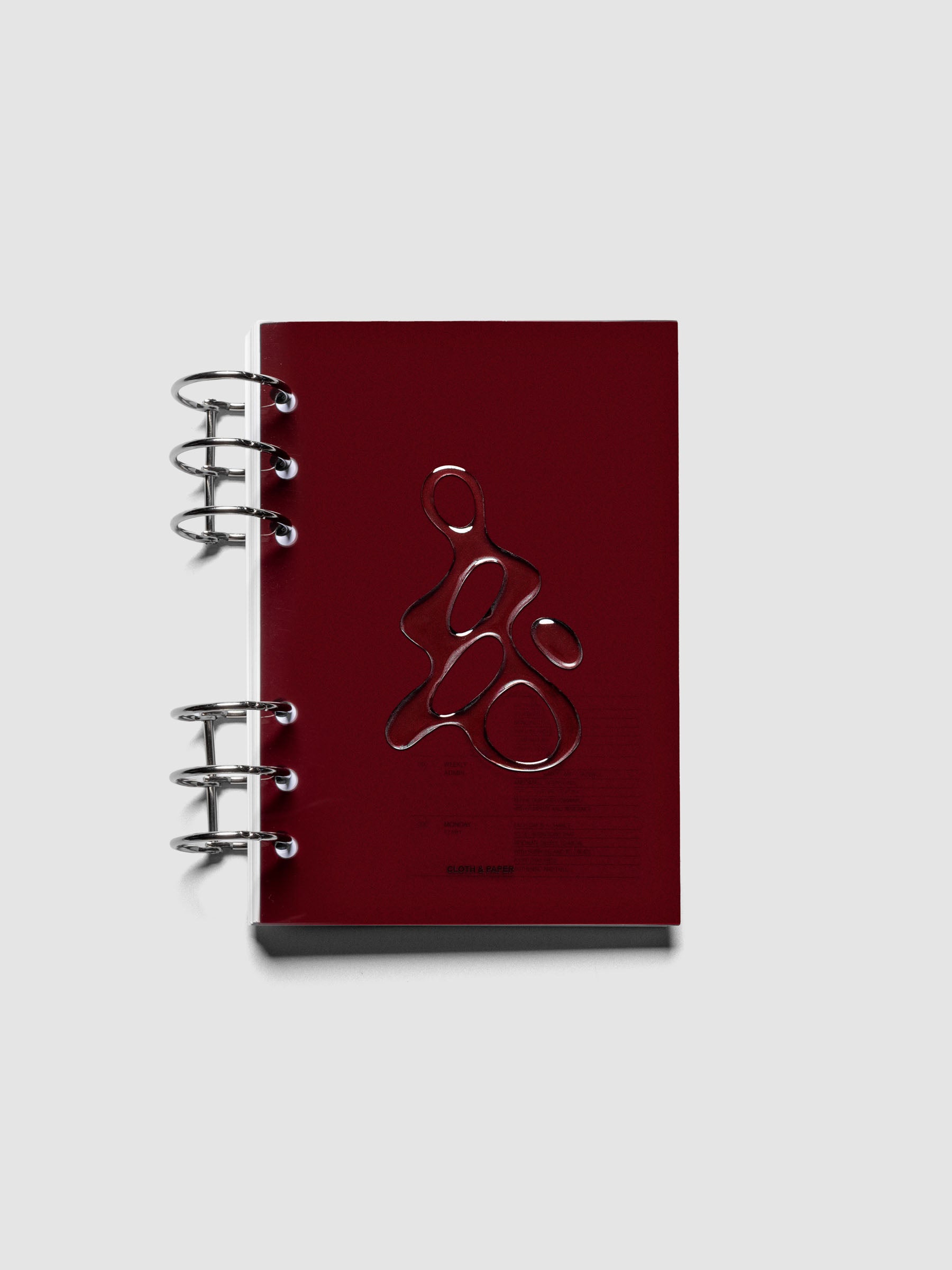 Dark red, semi-transparent, and glossy plastic planner dashboard with organic raised shape design in size Personal Wide shown ringbound.
