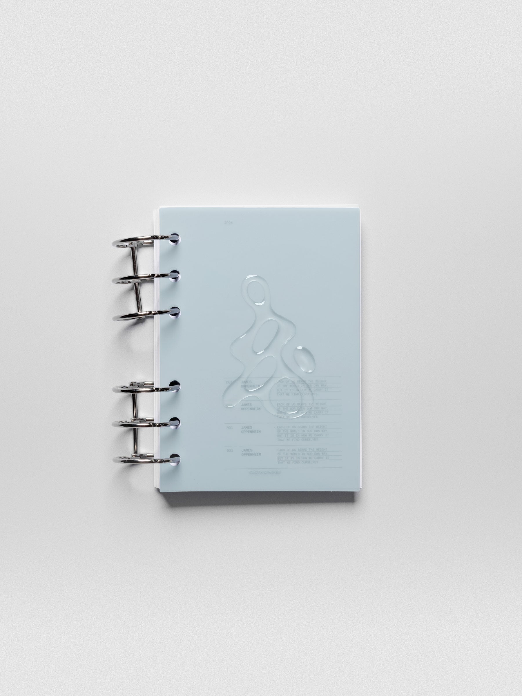 Light blue, semi-transparent, and glossy plastic planner dashboard with organic raised shape design in size A6 shown ringbound.