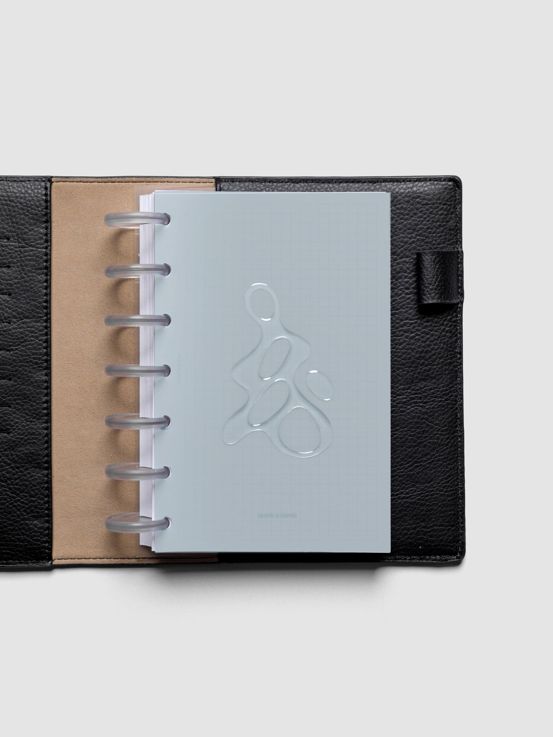 Light blue, semi-transparent, and glossy plastic planner dashboard with organic raised shape design in size HP mini discbound in a black leather folio.