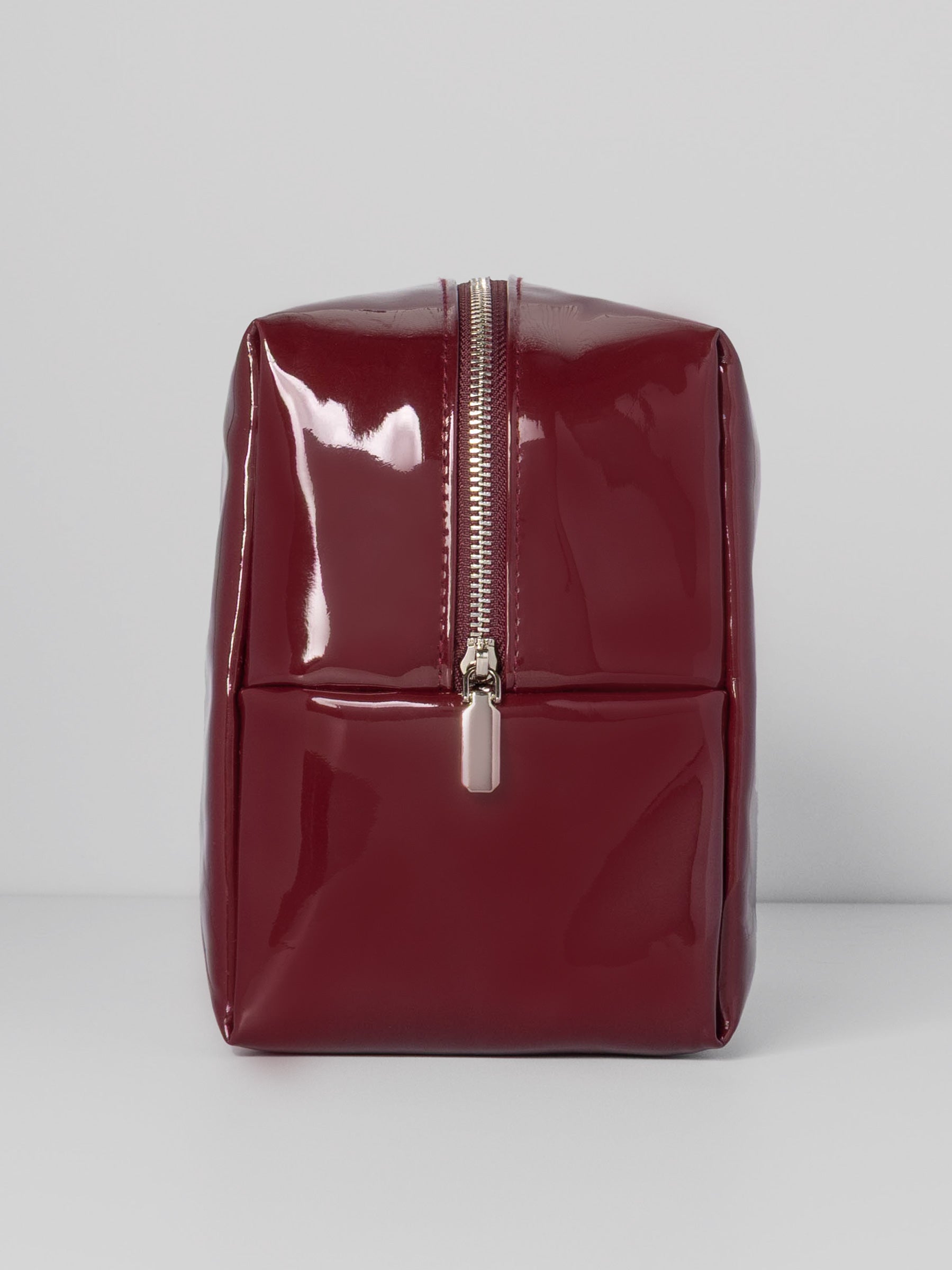 Deep red Lacquered Pouch shown from the side displaying a silver zipper closure.