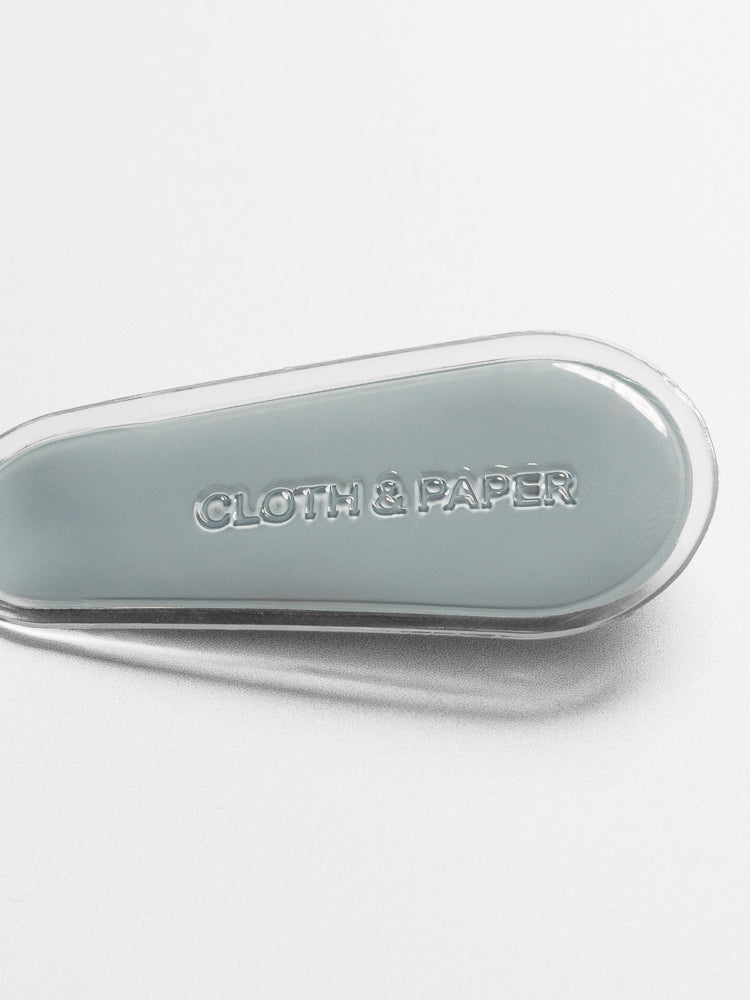 Blue magnetic bookmark shown closed from the back, laying flat on a neutral background with Cloth & Paper logo imprint.