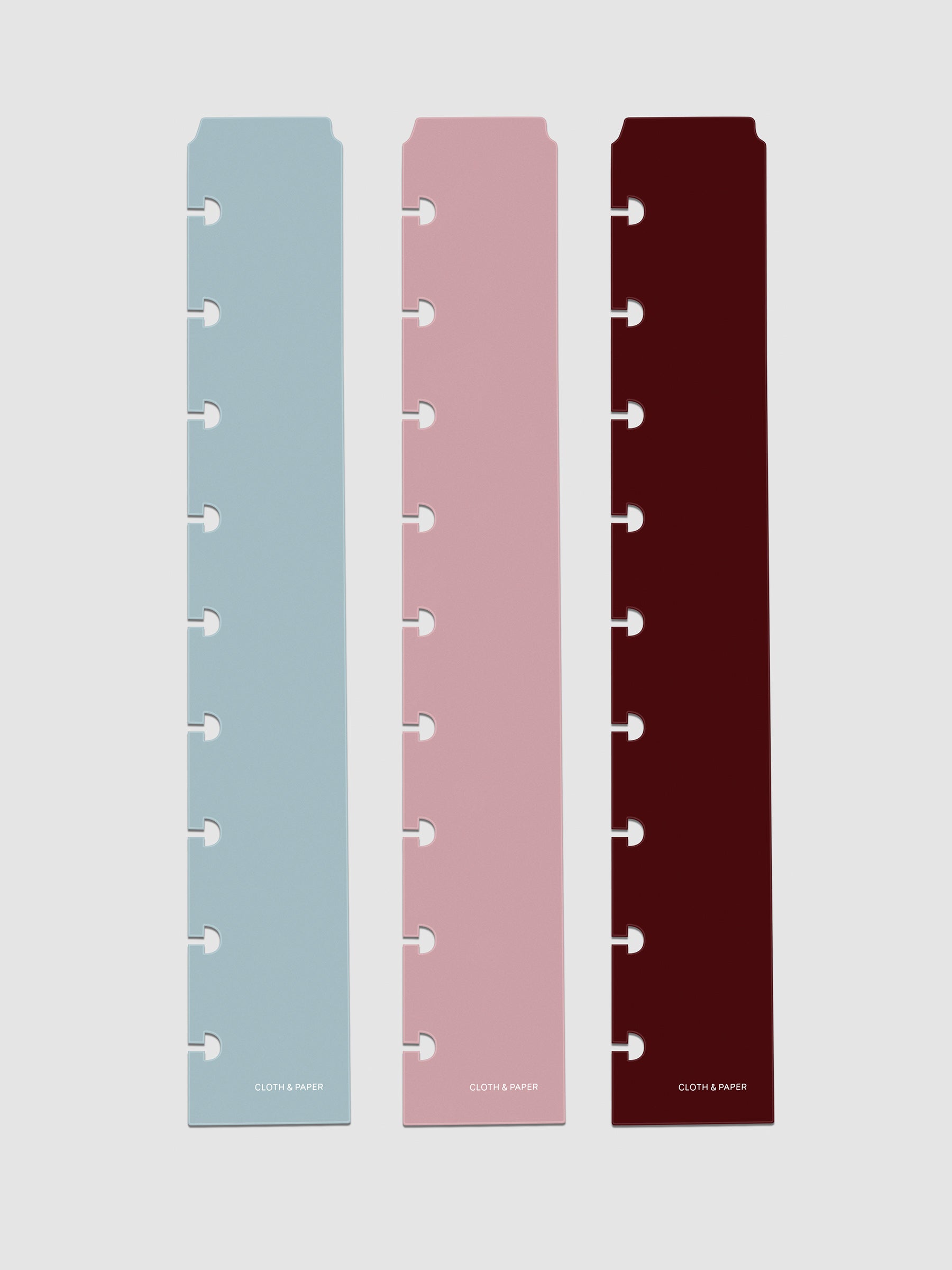 Set of three narrow page markers pre-punched for HP Classic planners in light blue, pink, and burgundy on a neutral background.