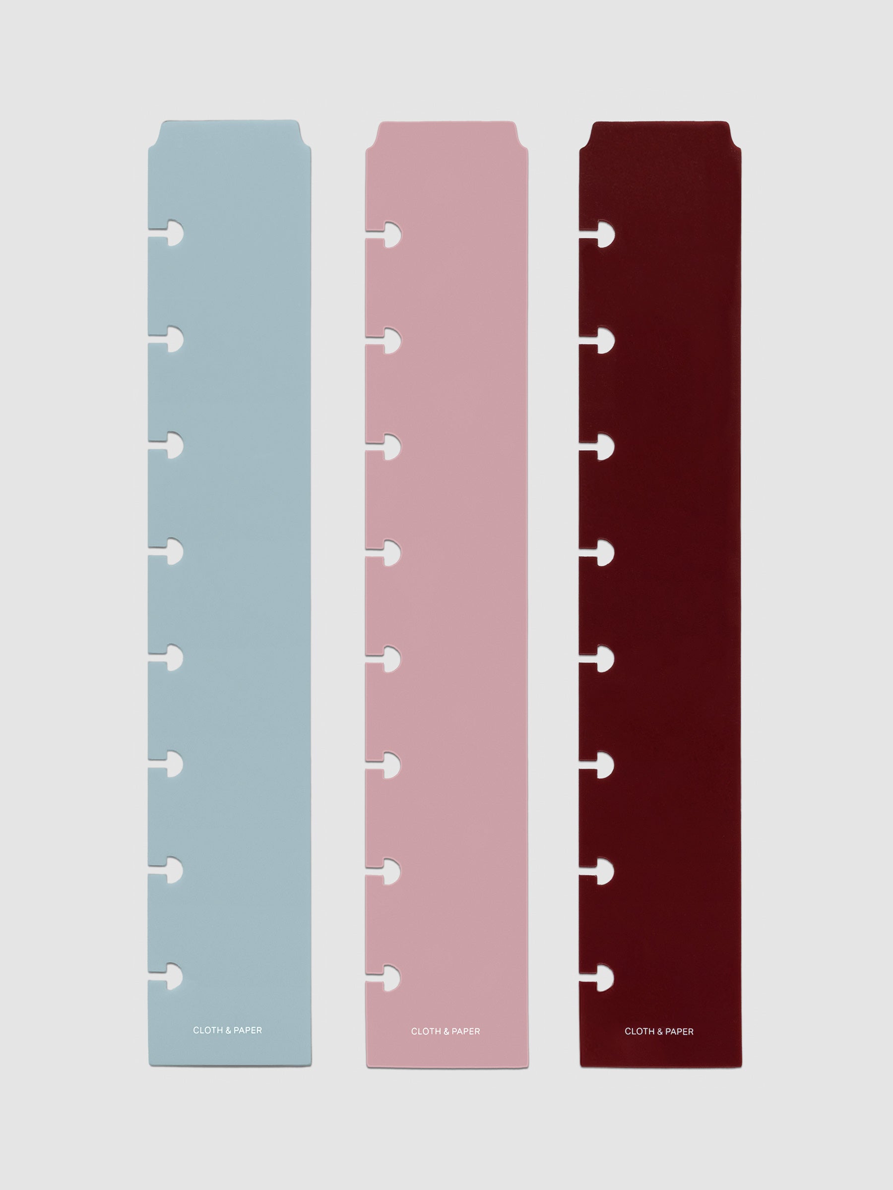 Set of three narrow page markers pre-punched for Half Letter planners in light blue, pink, and burgundy on a neutral background.