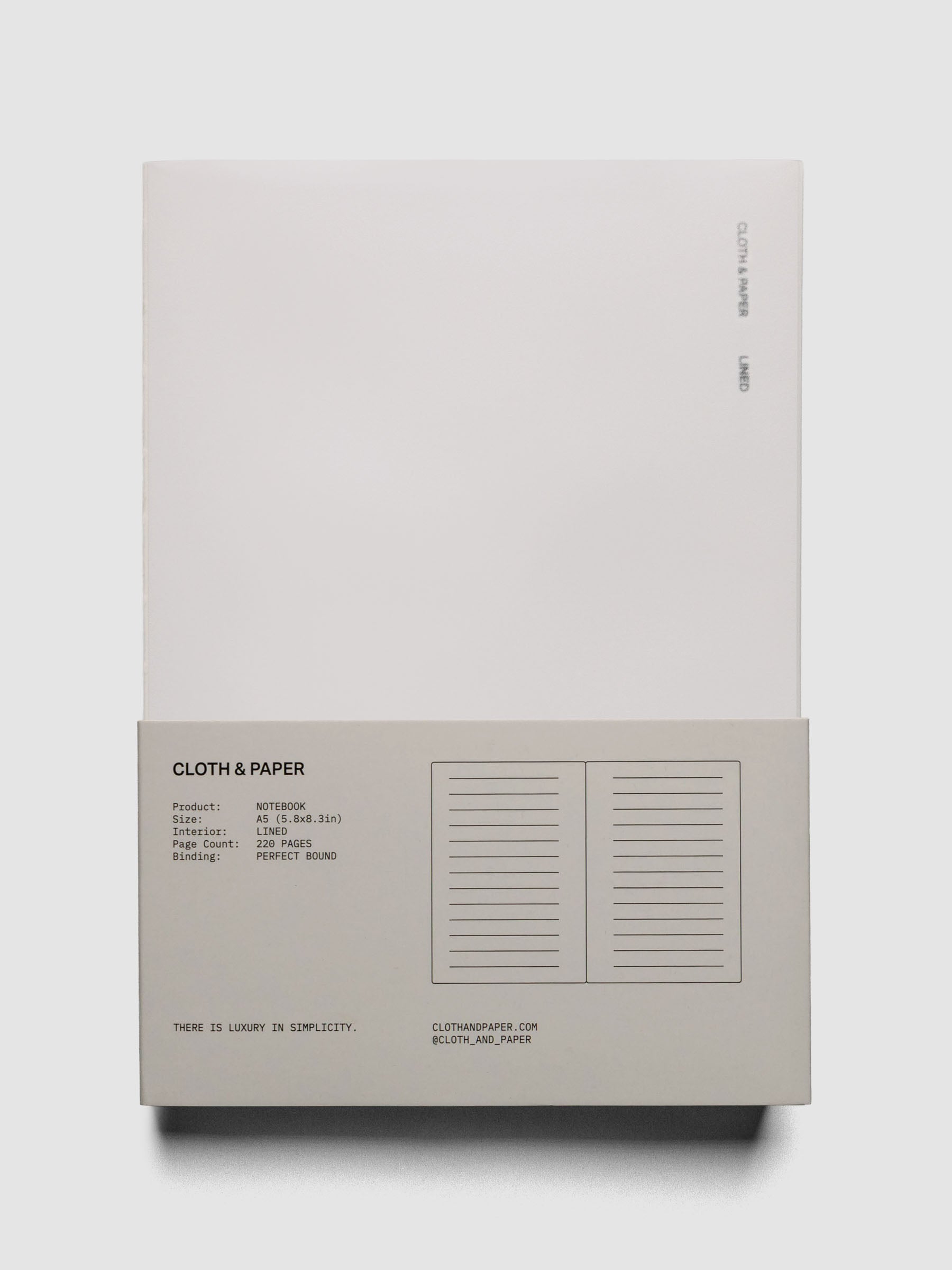 Perfect Bound Notebook | A5 | Lined | Ash shown open, laid flat, on a neutral background in packaging.