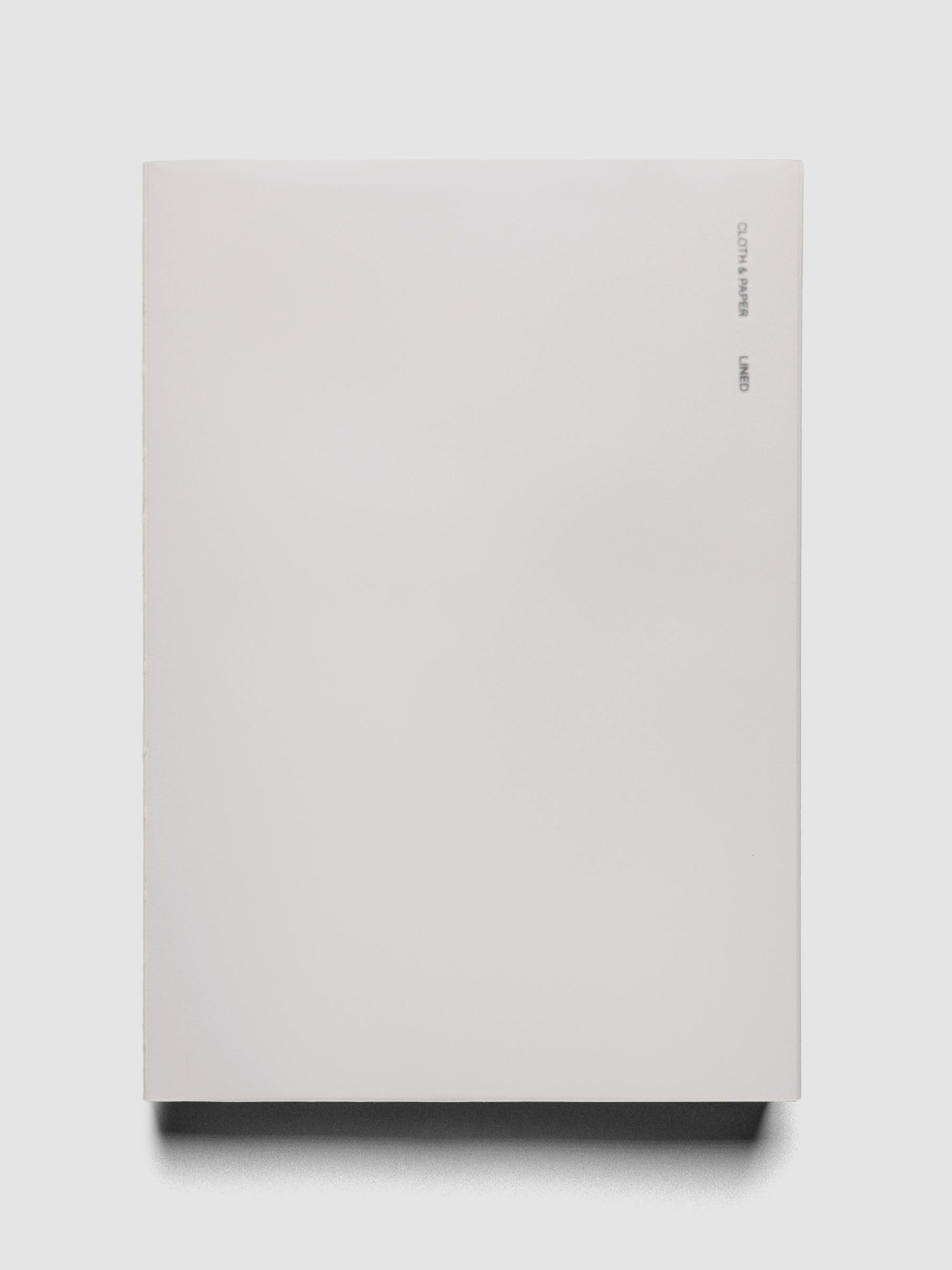 Perfect Bound Notebook | A5 | Lined | Ash shown closed, laying flat on a neutral background.