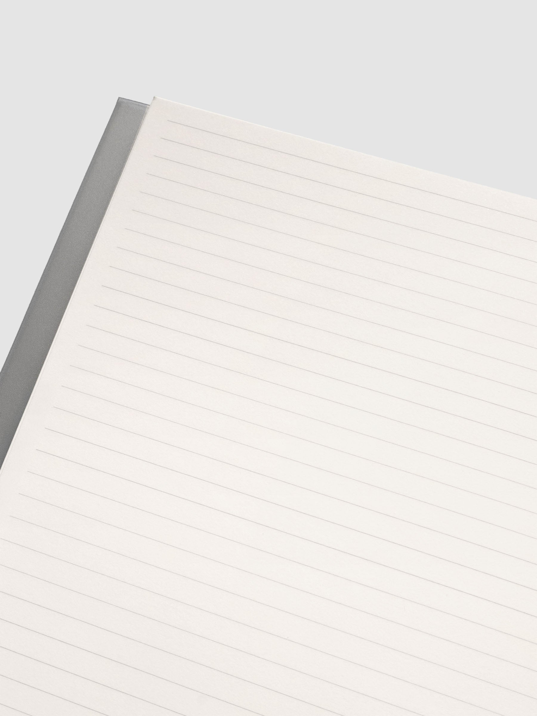 Close up of the Perfect Bound Notebook | A5 | Lined | Ash shown open, laid flat, on a neutral background displaying the lined notes layout.